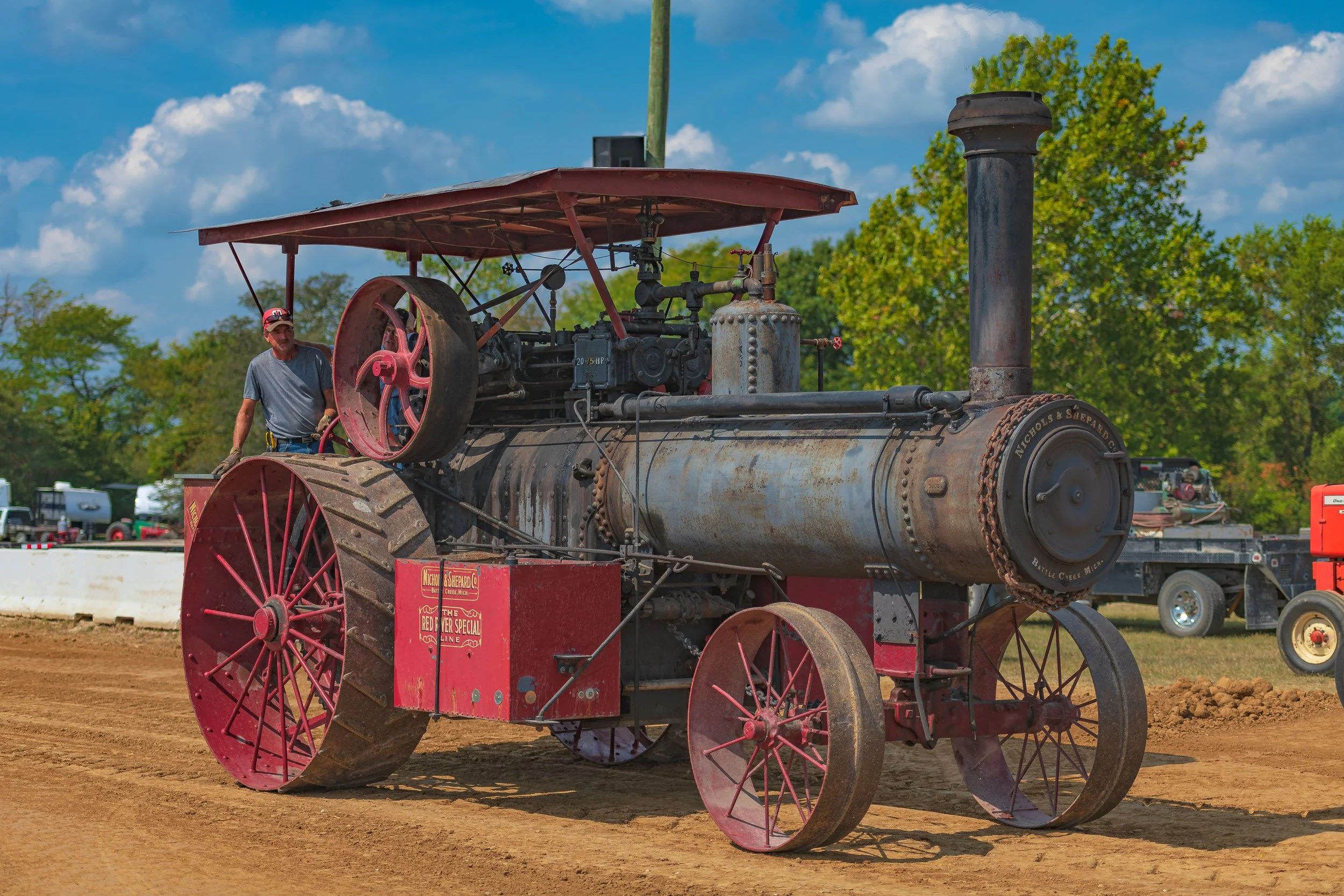 A side view of a steam traction engine with red wheels and a red canopy at the 2022 Old Thresher Days.