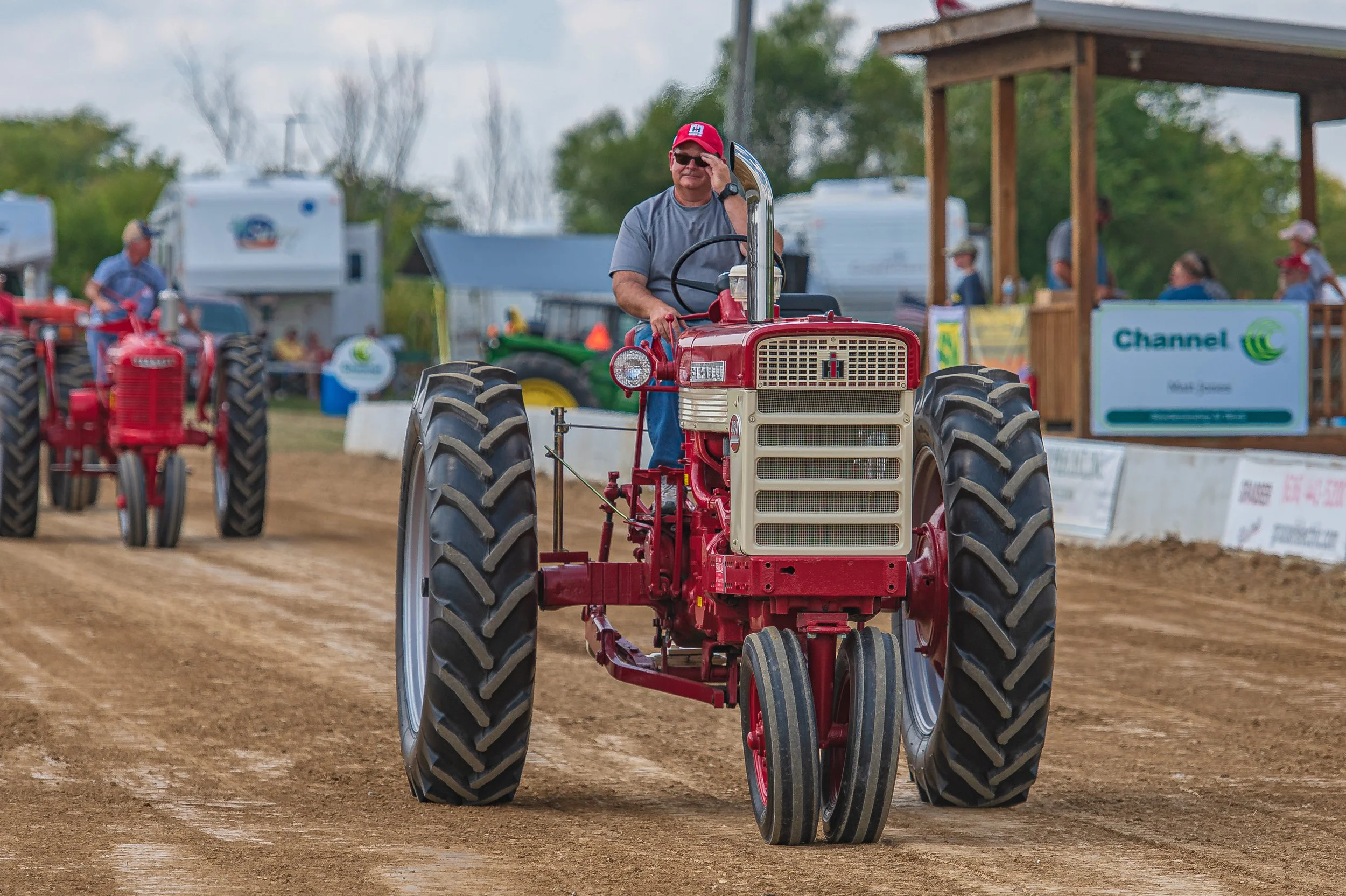 A red tractor leads a line of tractors around the track at the 2022 Old Thresher Days.