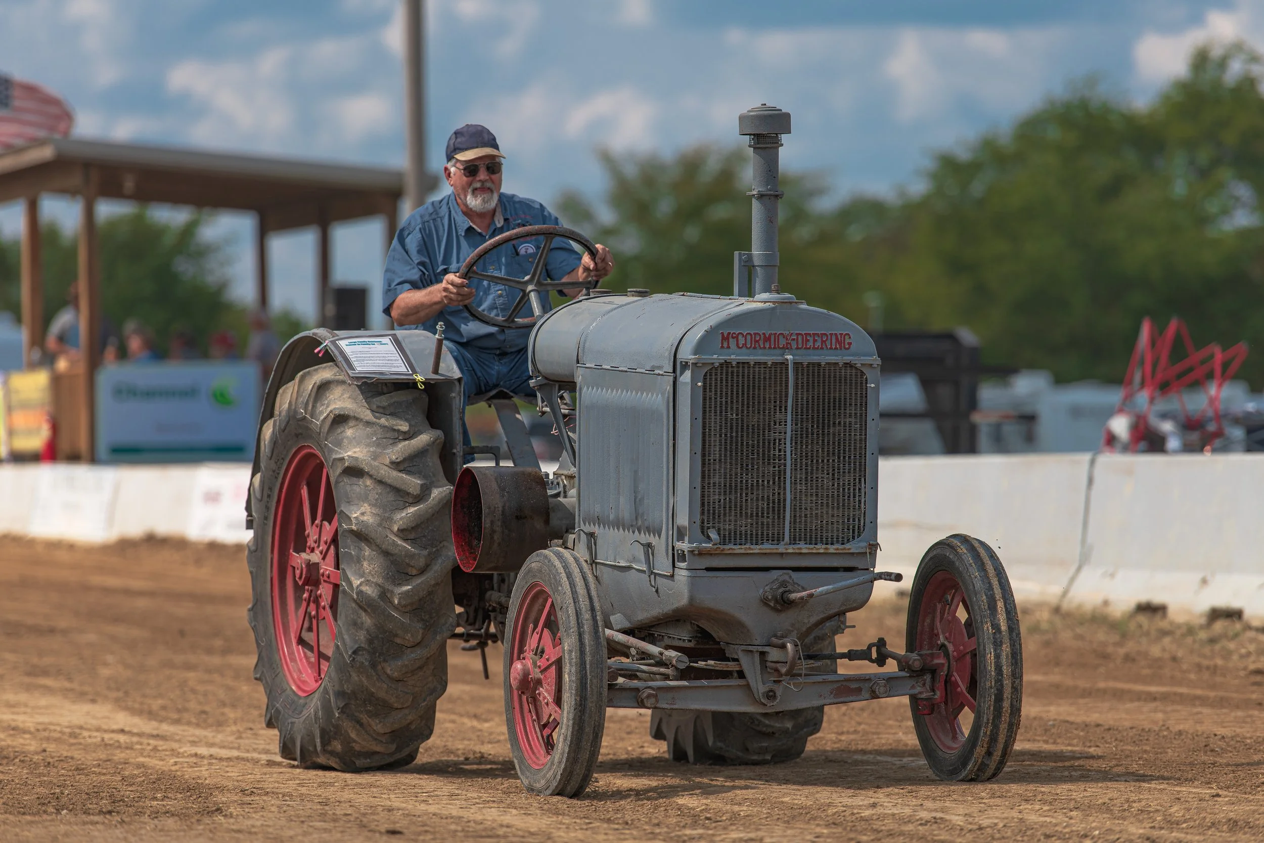 A gray vintage tractor with red wheels passes the viewing area at the 2022 Old Thresher Days.