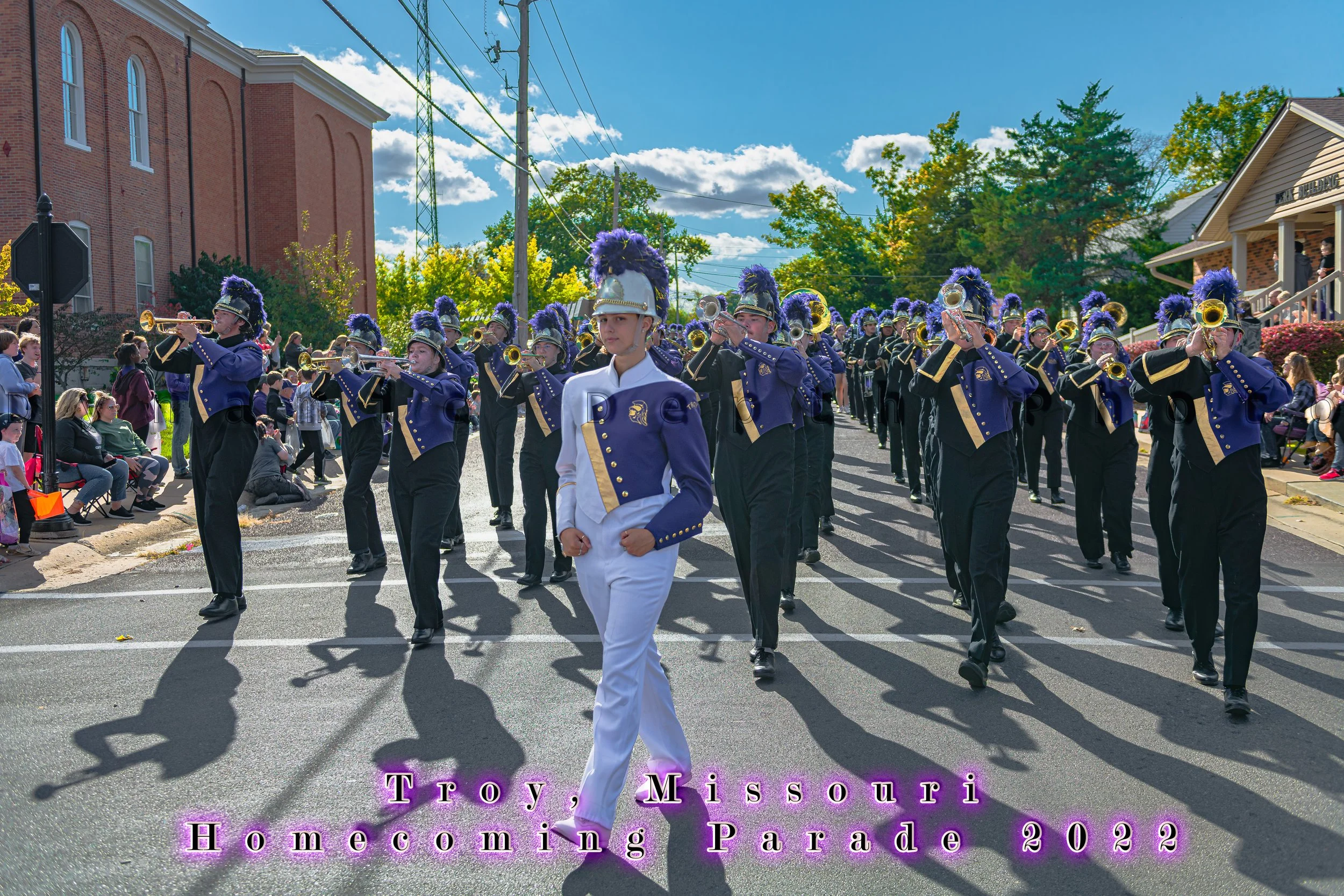 A marcher in a white uniform leads rows of musicians in blue and gold during the 2022 Troy Homecoming Parade.