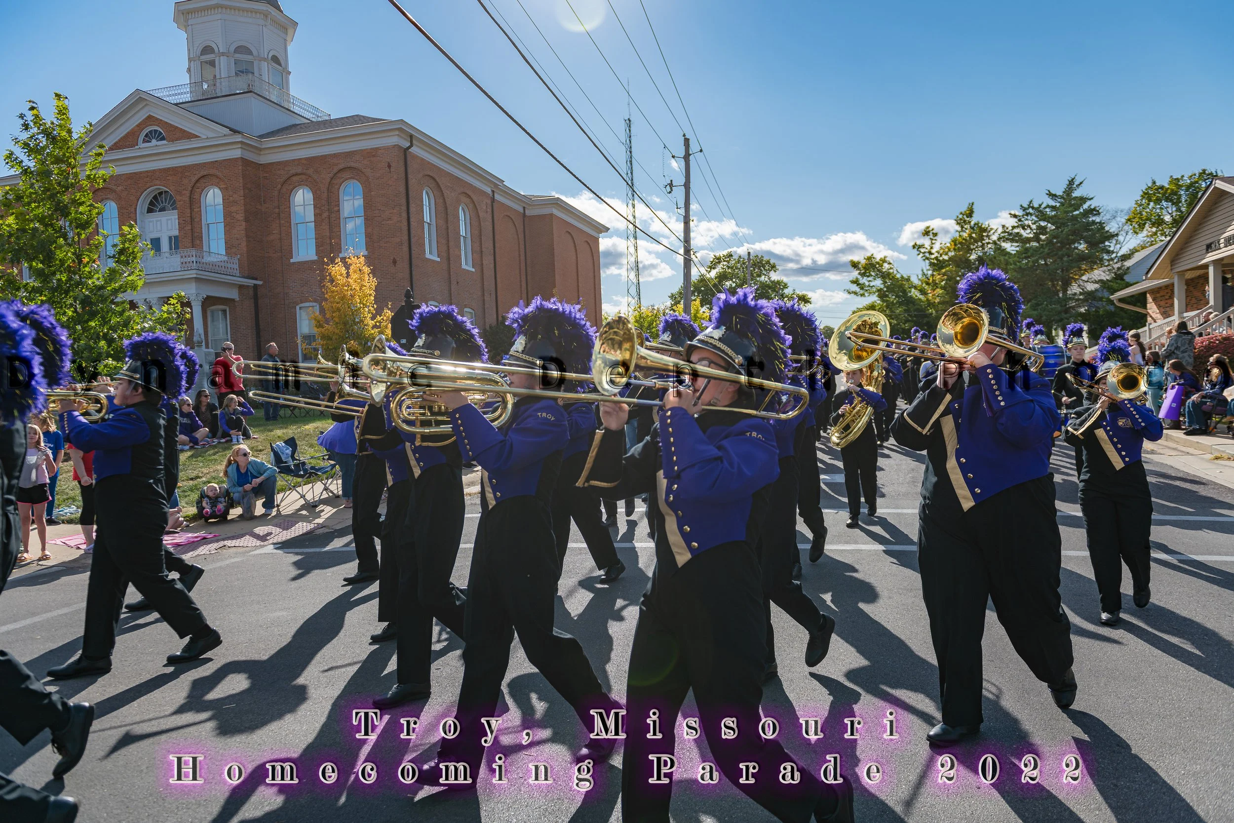 Trombone players perform while marching past the red-brick building during the 2022 Troy Homecoming Parade.