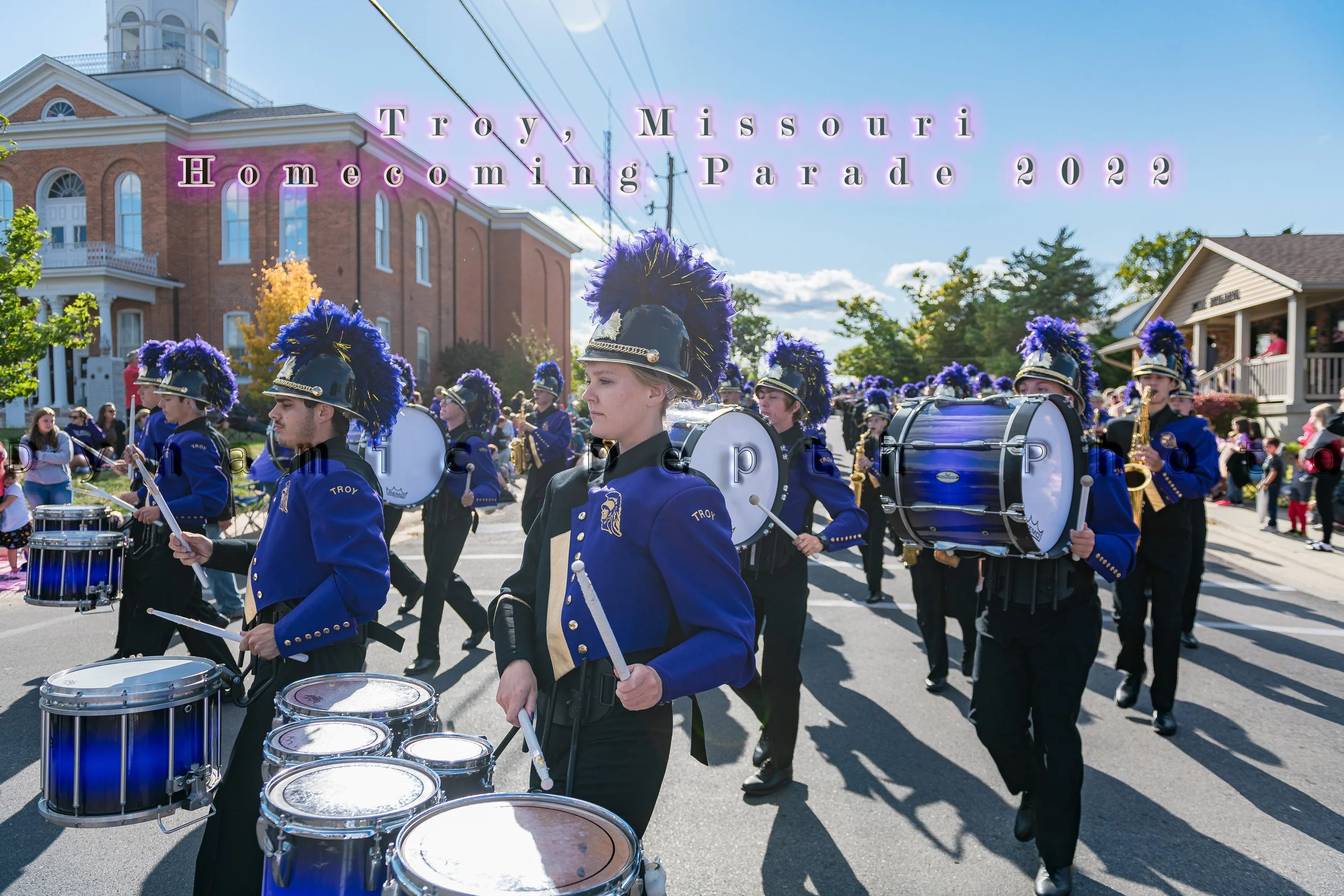 A drummer carrying multiple tenor drums leads a row of bass drummers during the 2022 Troy Homecoming Parade.