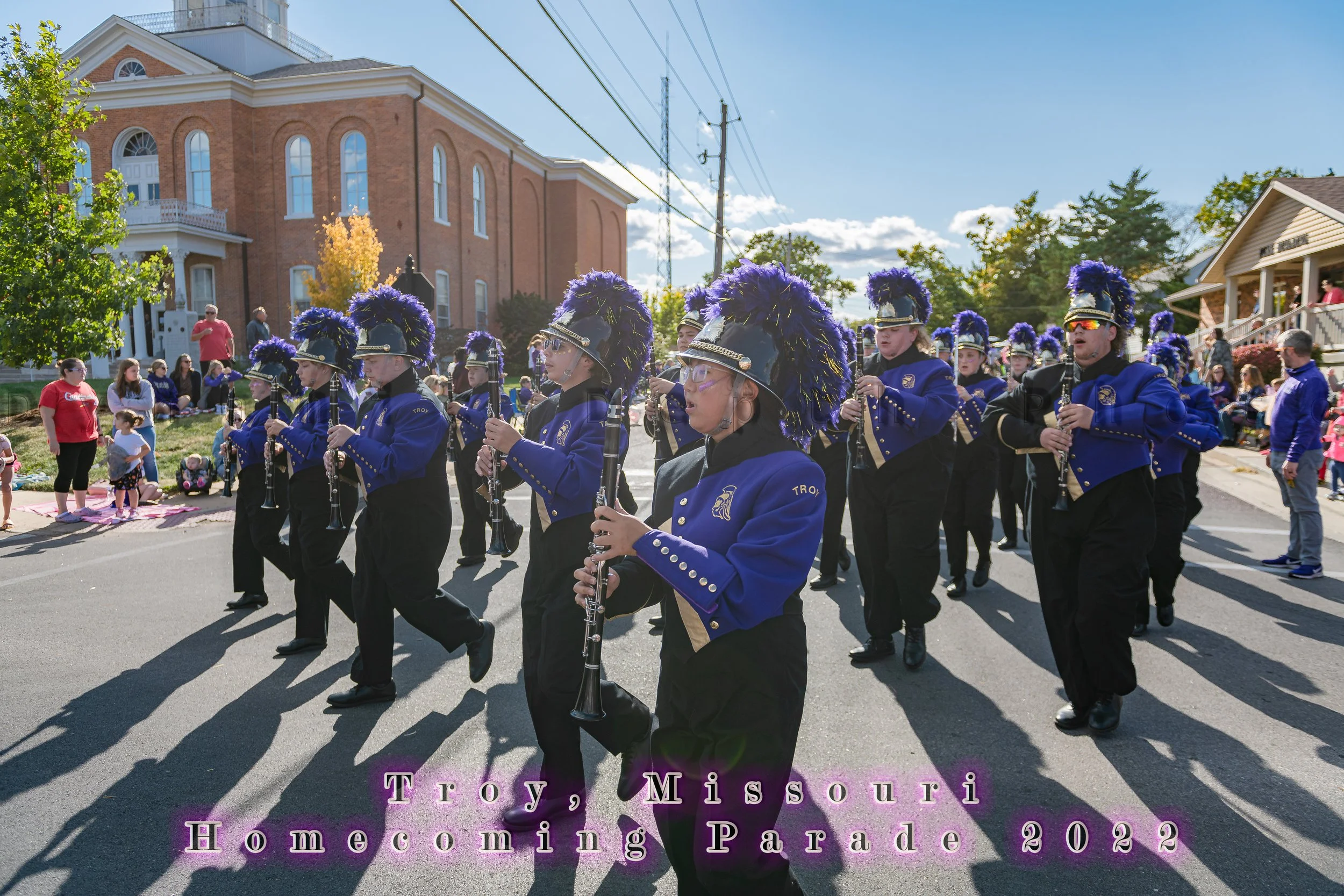 Clarinet players perform in blue-and-gold uniforms with purple plumes during the 2022 Troy Homecoming Parade.
