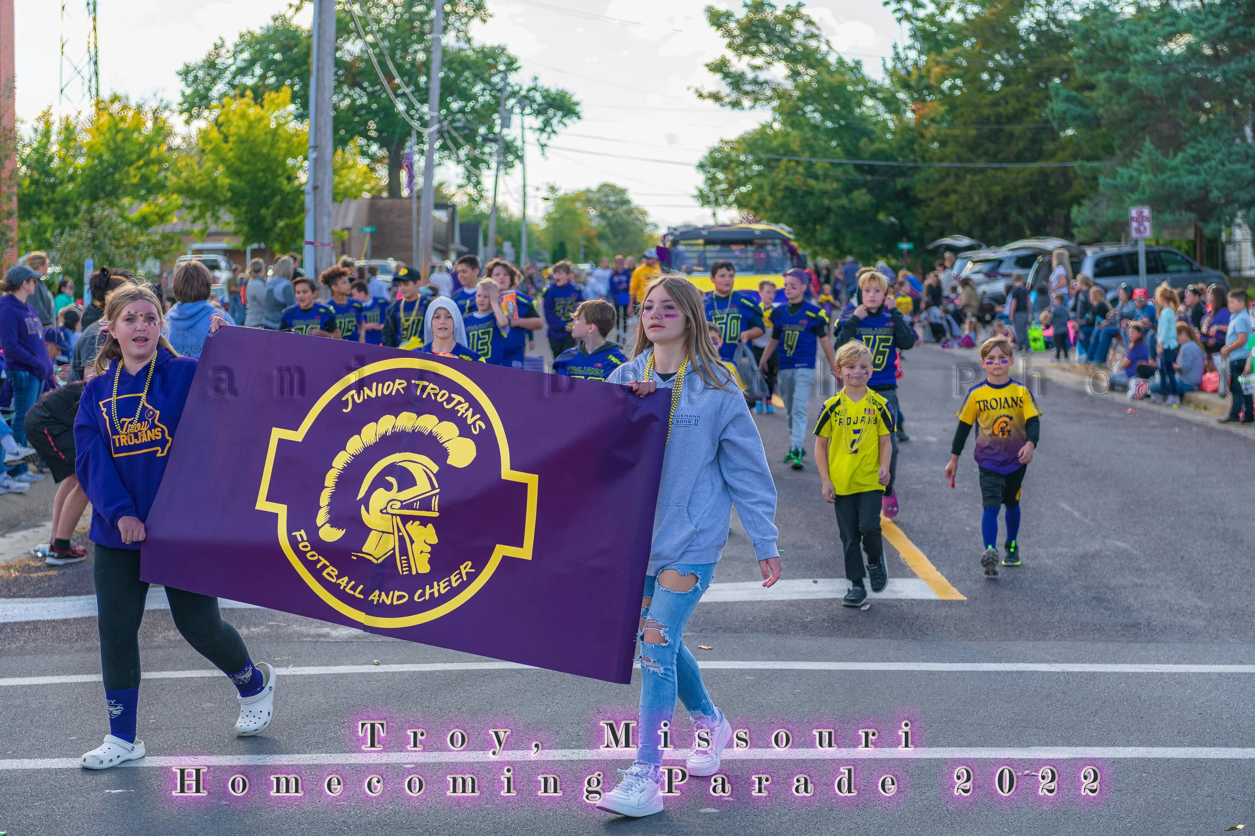 Marchers carry a Junior Trojans Football and Cheer banner during the 2022 Troy Homecoming Parade.