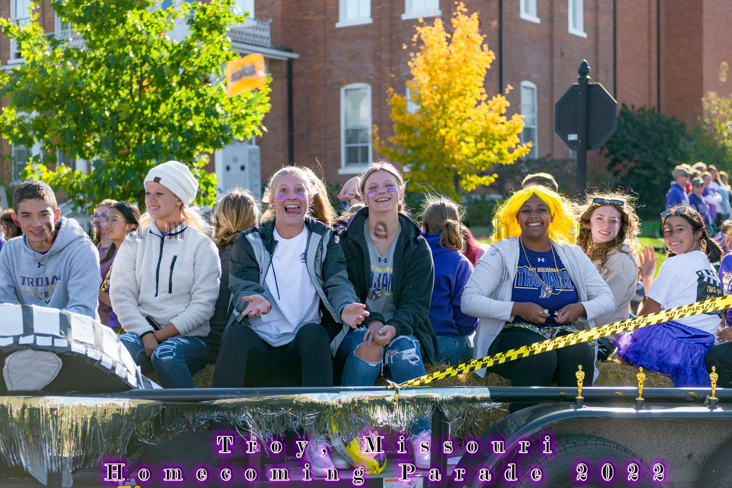 Passengers sit along the edge of a float decorated in school colors during the 2022 Troy Homecoming Parade.