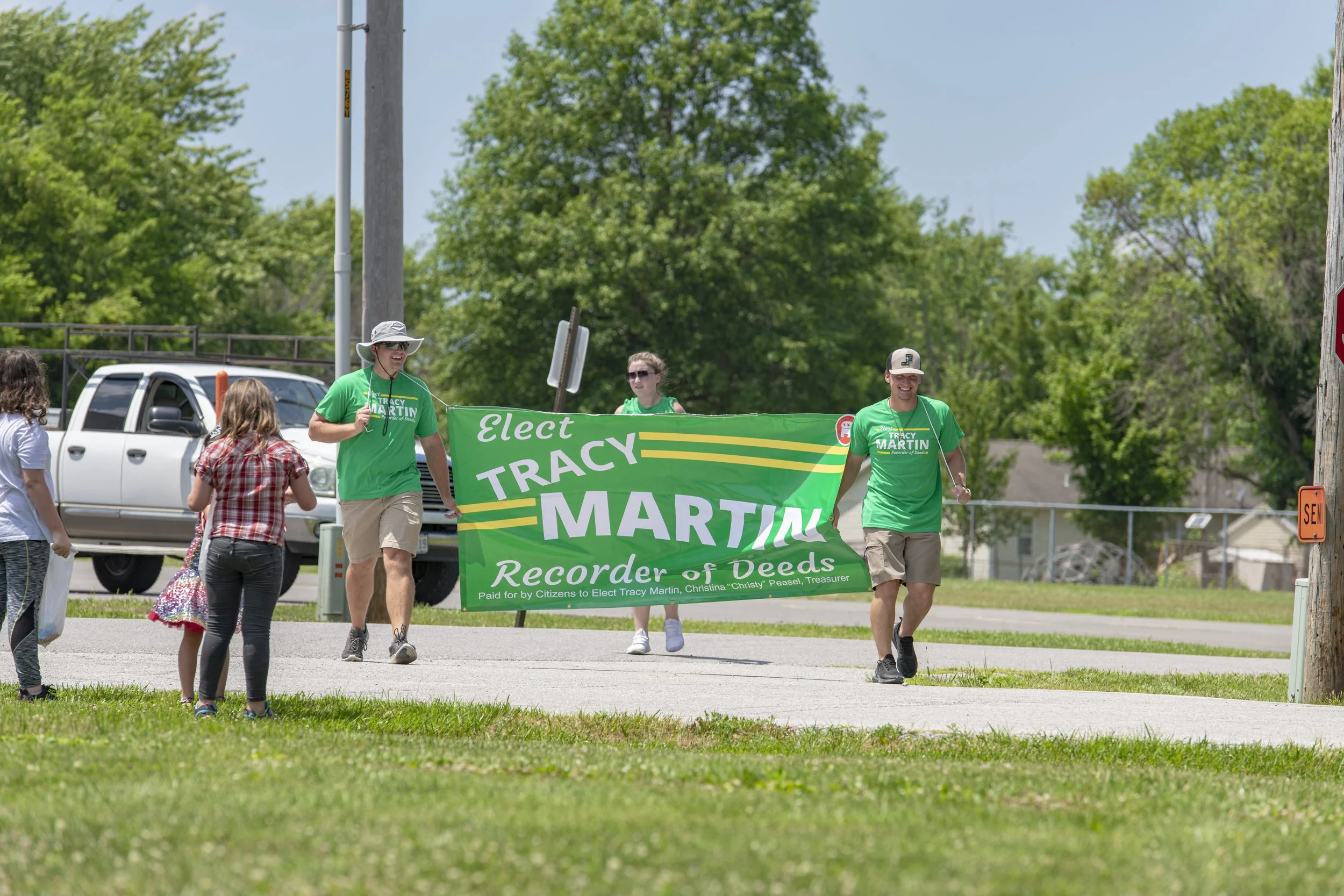 Marchers carry a green election campaign banner during the 2022 July 4th Hawk Point Parade.