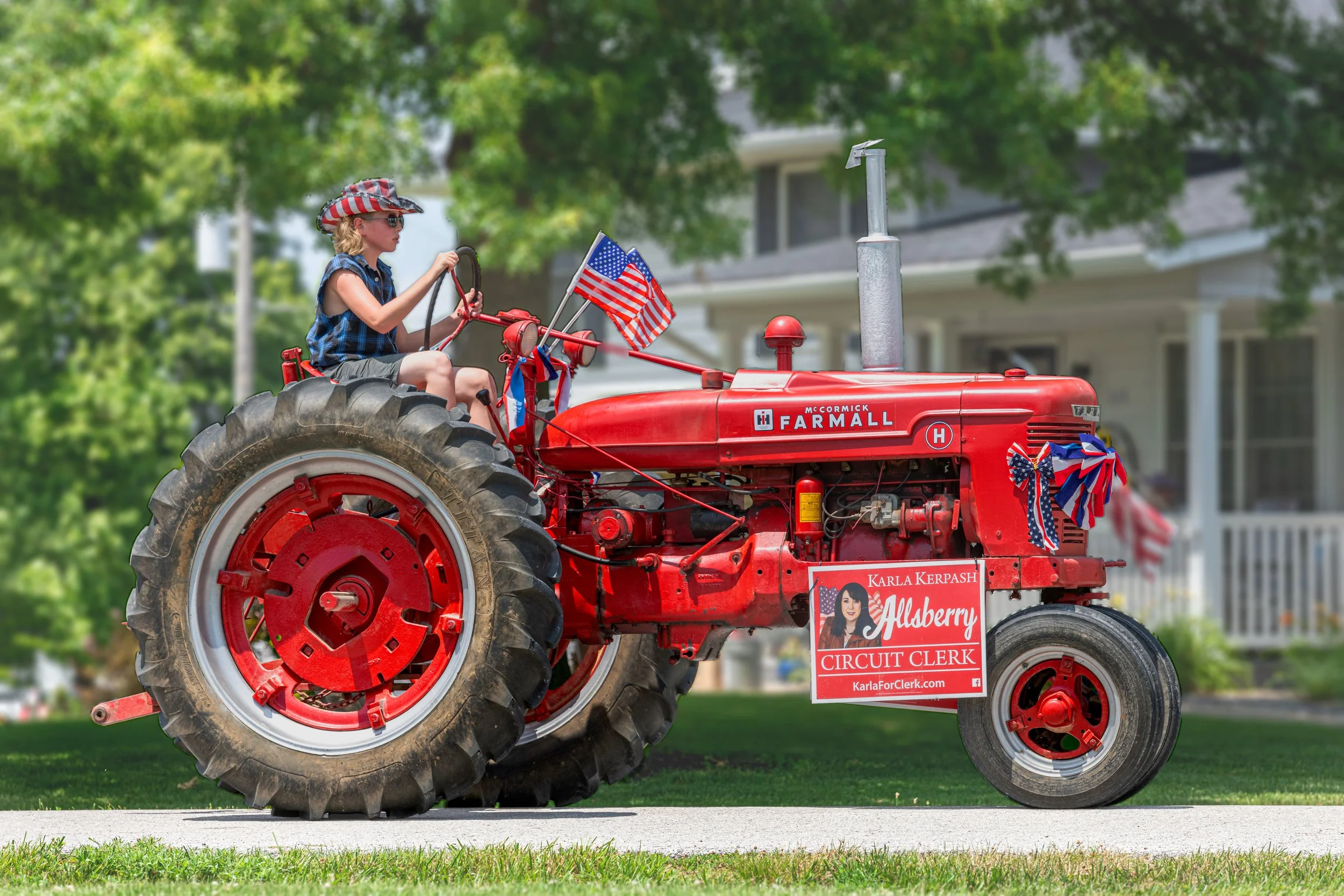 A red Farmall tractor carries flags and patriotic decorations during the 2022 July 4th Hawk Point Parade.