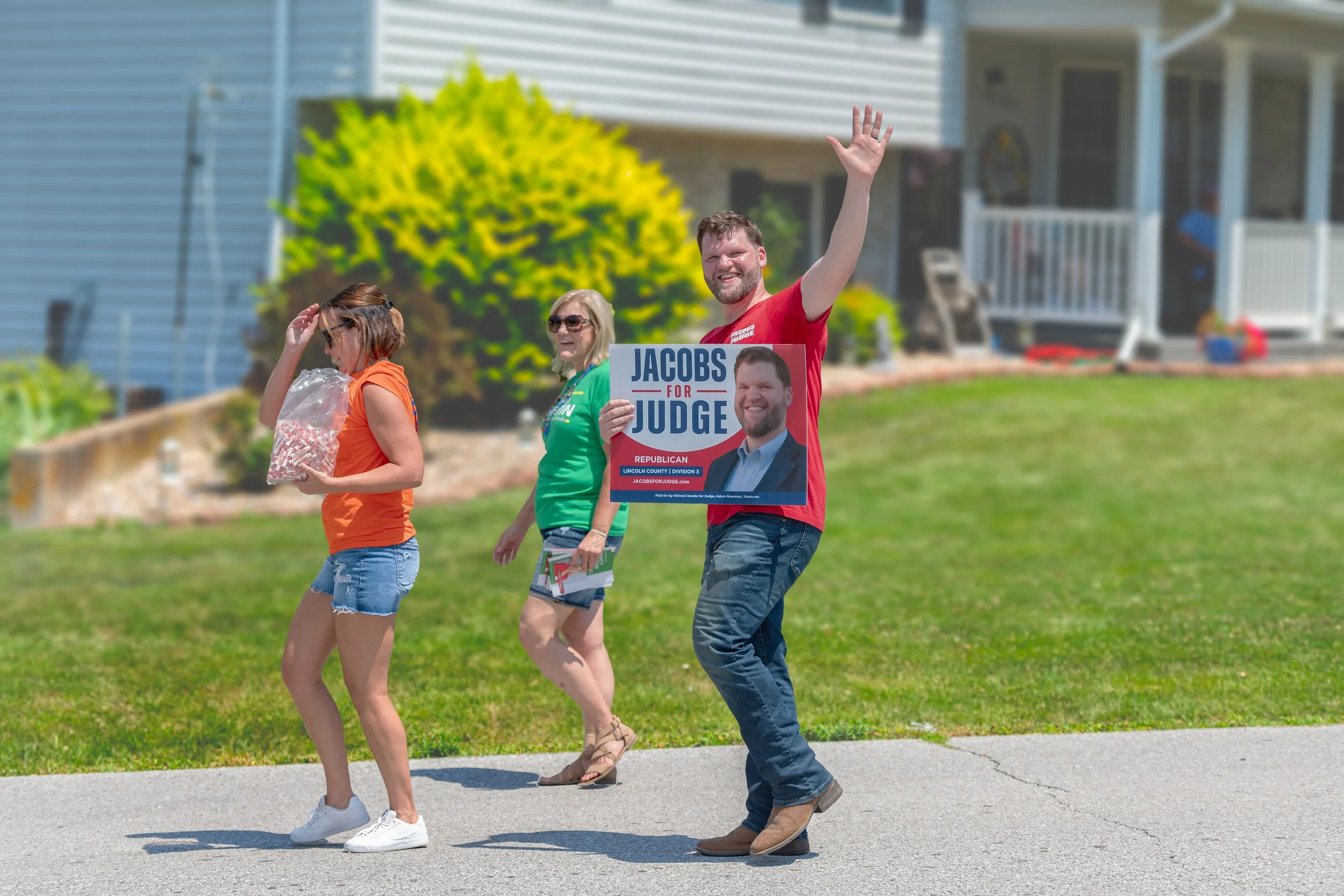 A marcher waves while carrying a campaign sign during the 2022 July 4th Hawk Point Parade.