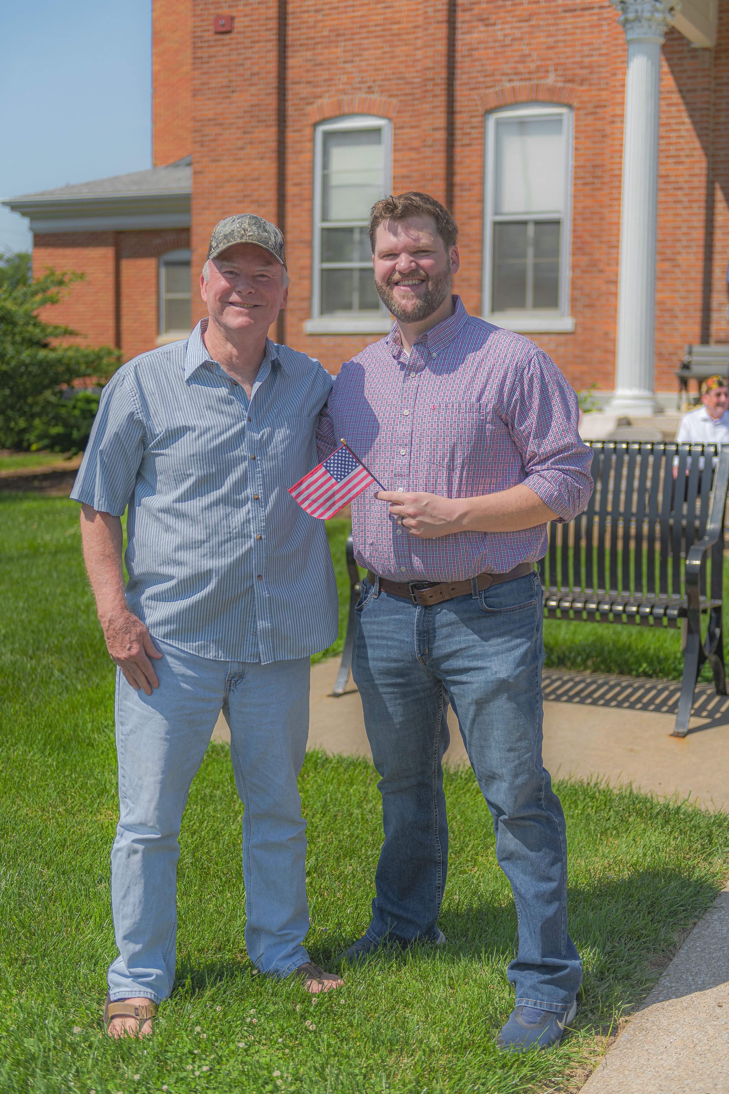 Two attendees pose on the lawn, one holding a small American flag at the 2022 Lincoln County Memorial Day service.