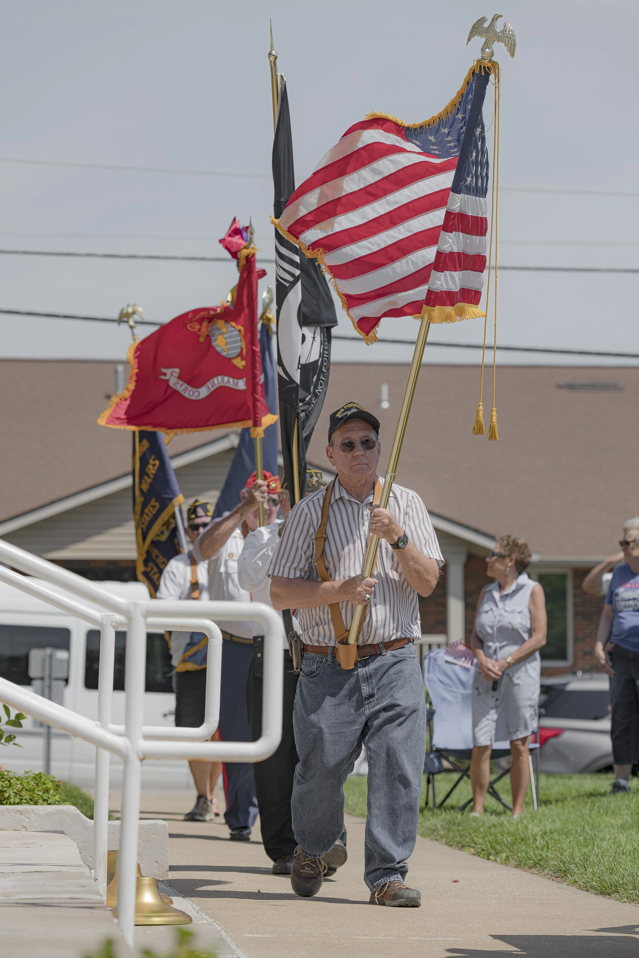 Flag bearers walk beside the steps carrying American and service flags at the 2022 Lincoln County Memorial Day service.