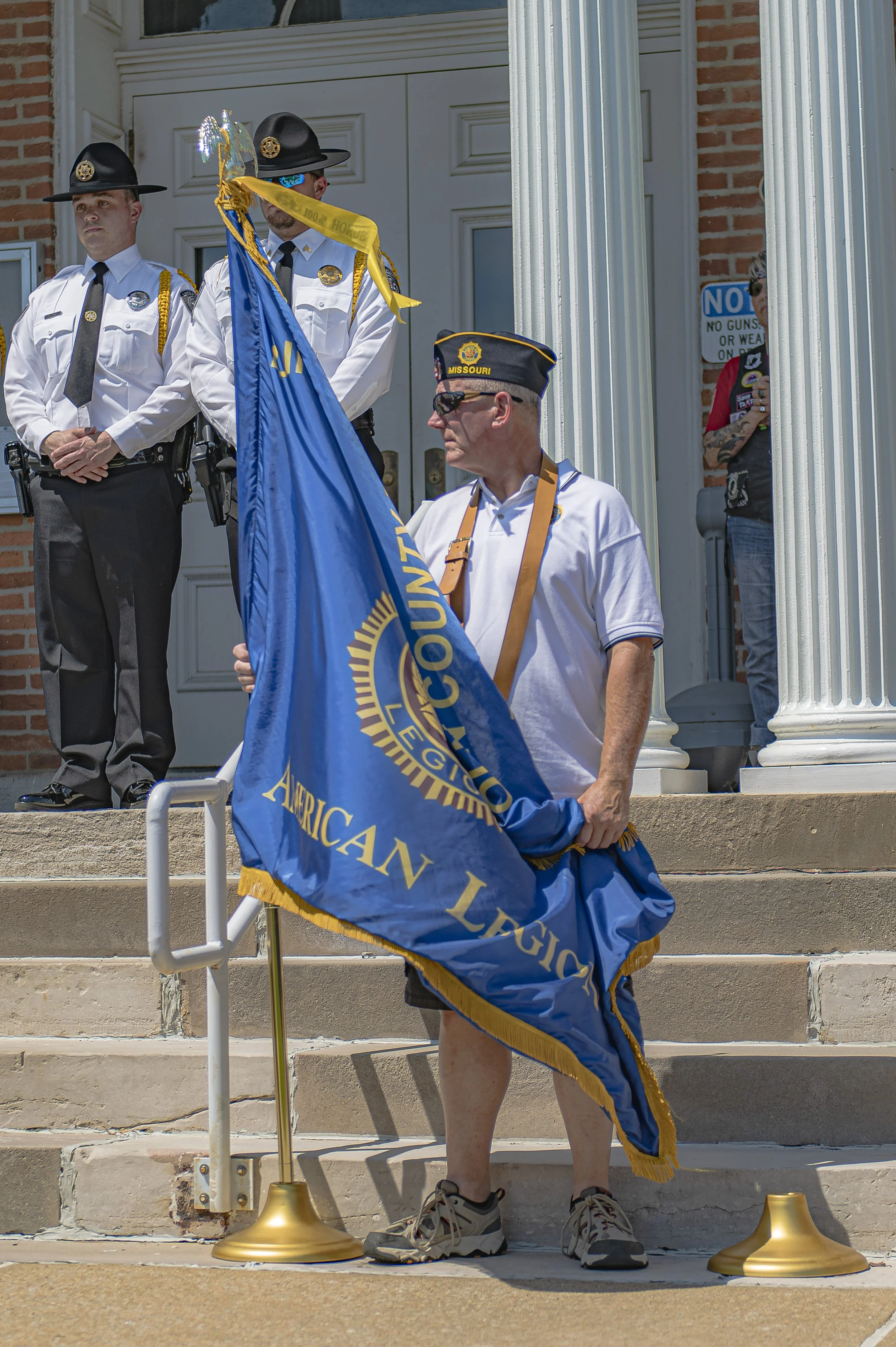 A flag bearer holds a blue American Legion banner beside the steps at the 2022 Lincoln County Memorial Day service.