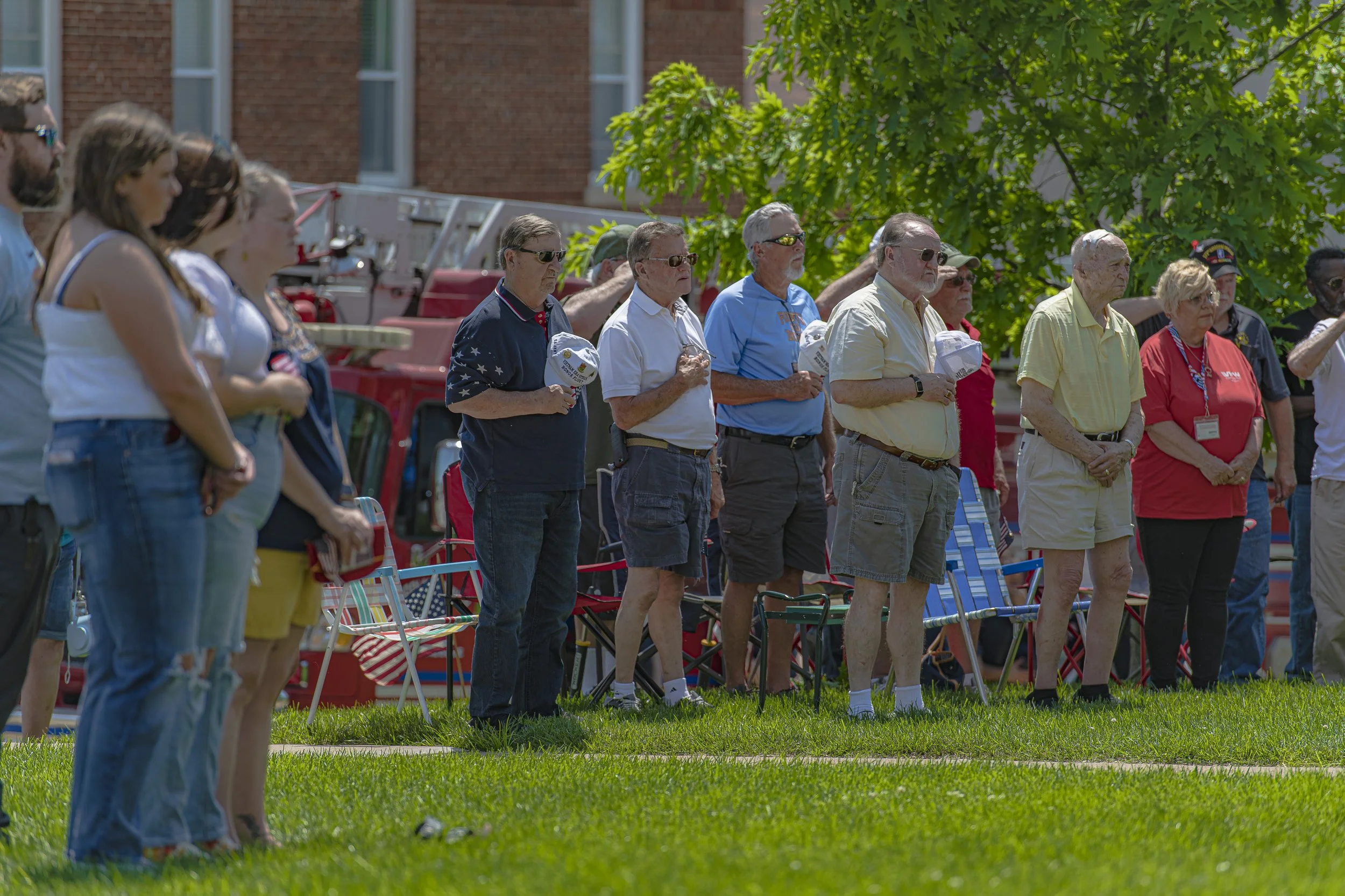 Attendees stand with heads lowered on the lawn at the 2022 Lincoln County Memorial Day service.