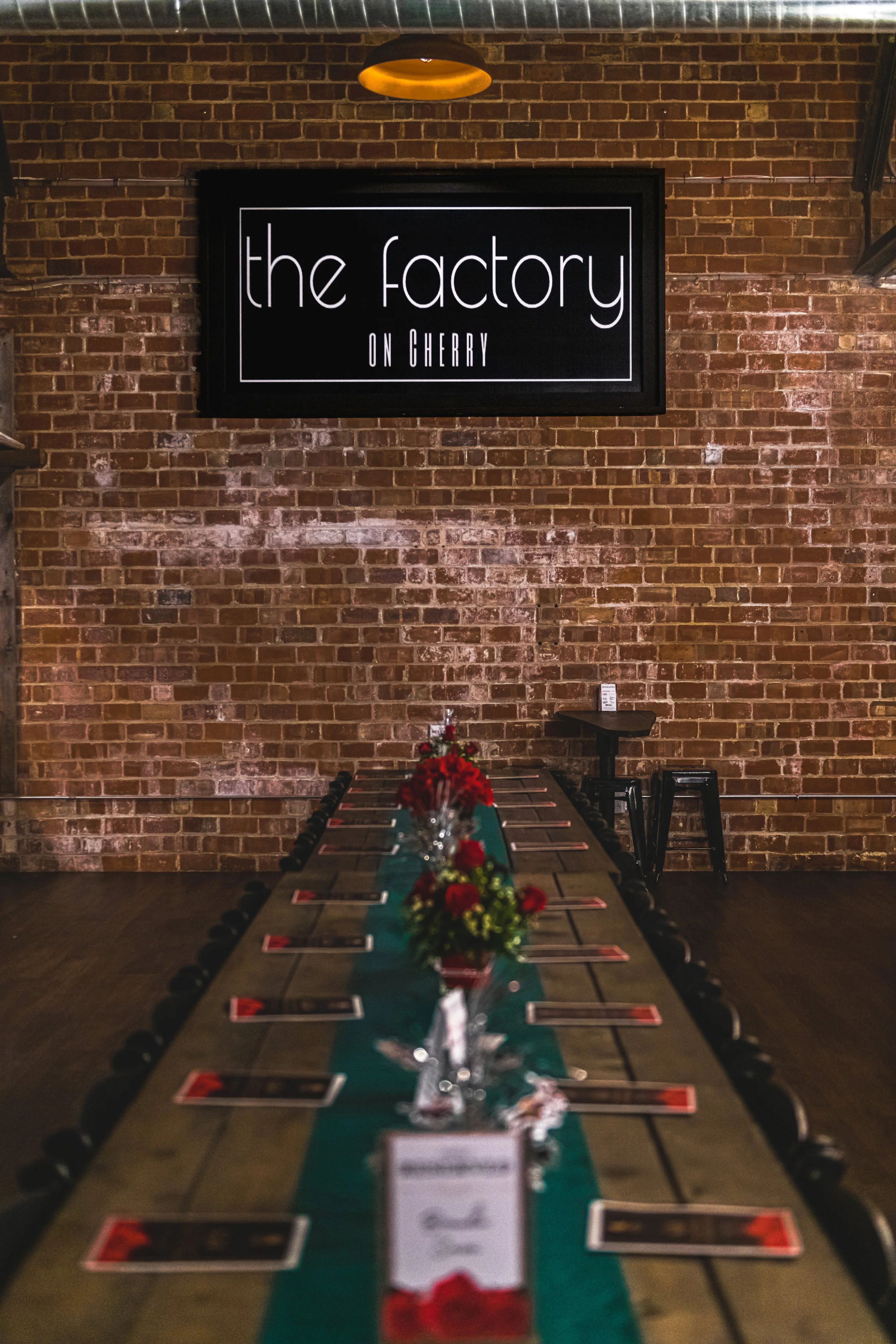 A decorated banquet table leads toward a brick wall and a sign reading “the factory on cherry.”