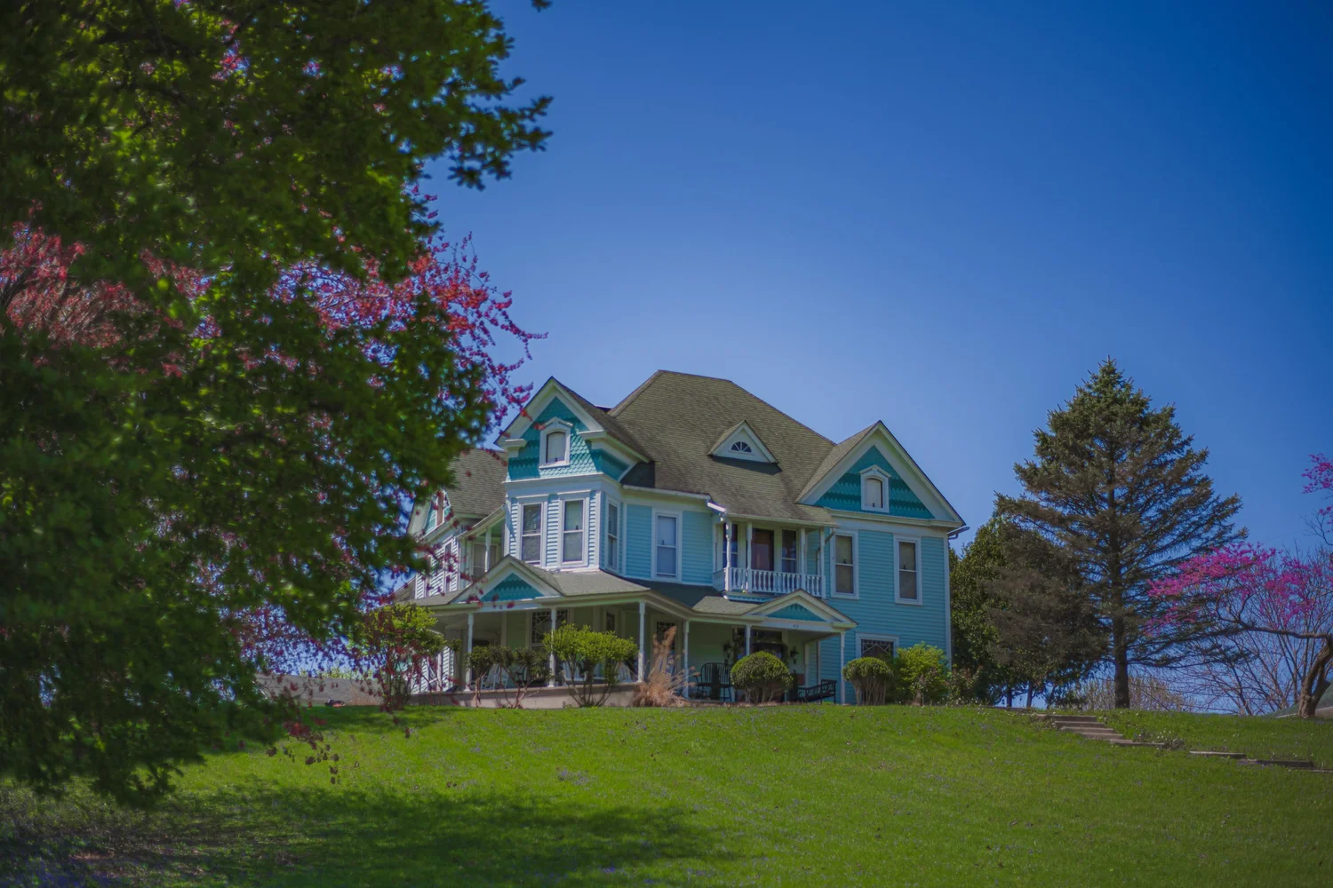 Blue Victorian House Above a Green Lawn. Visible: blue house, Victorian house, front porch.