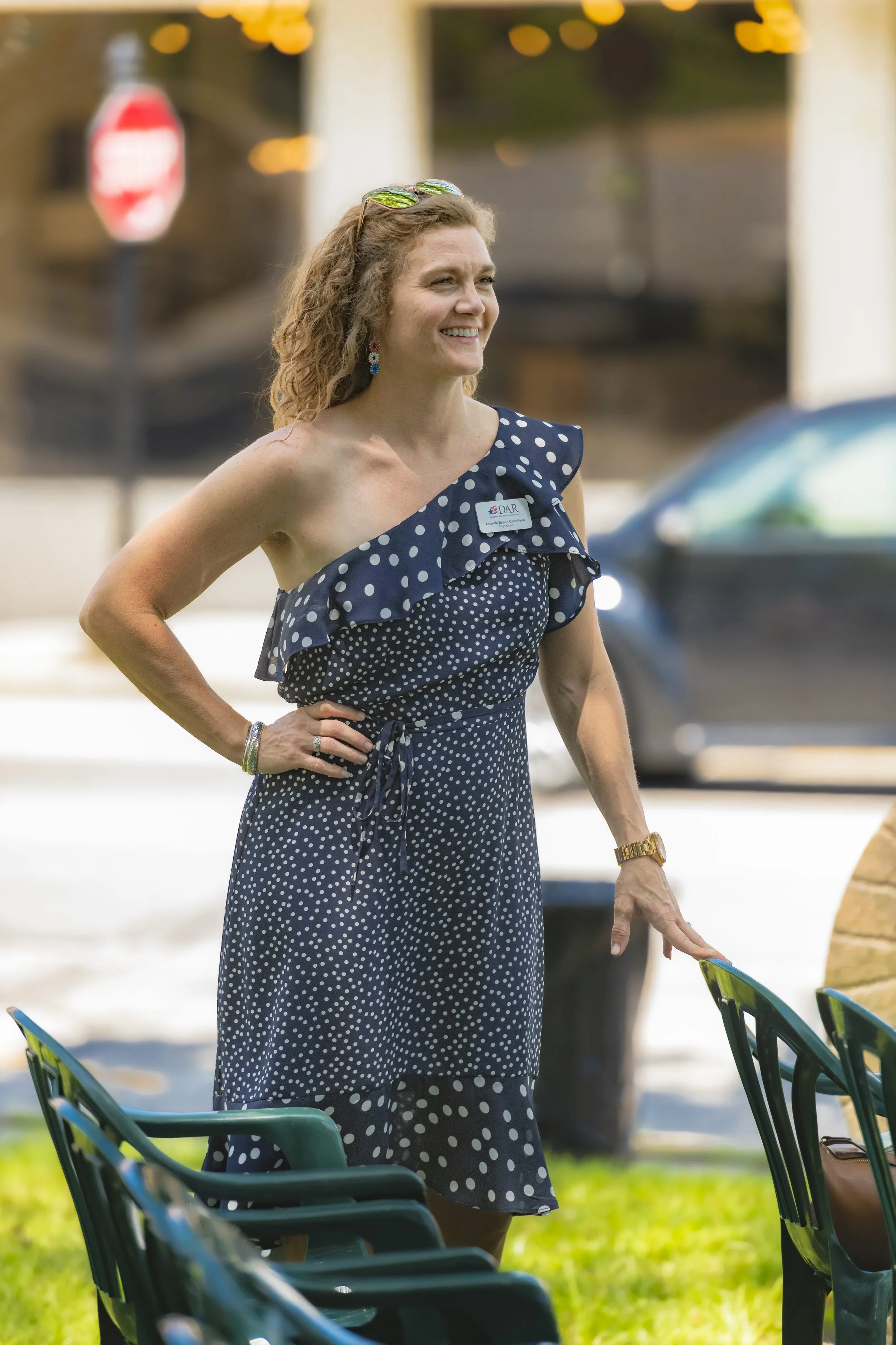 An attendee in a navy patterned dress stands beside the chairs at the 2022 Daughters of the American Revolution ceremony.