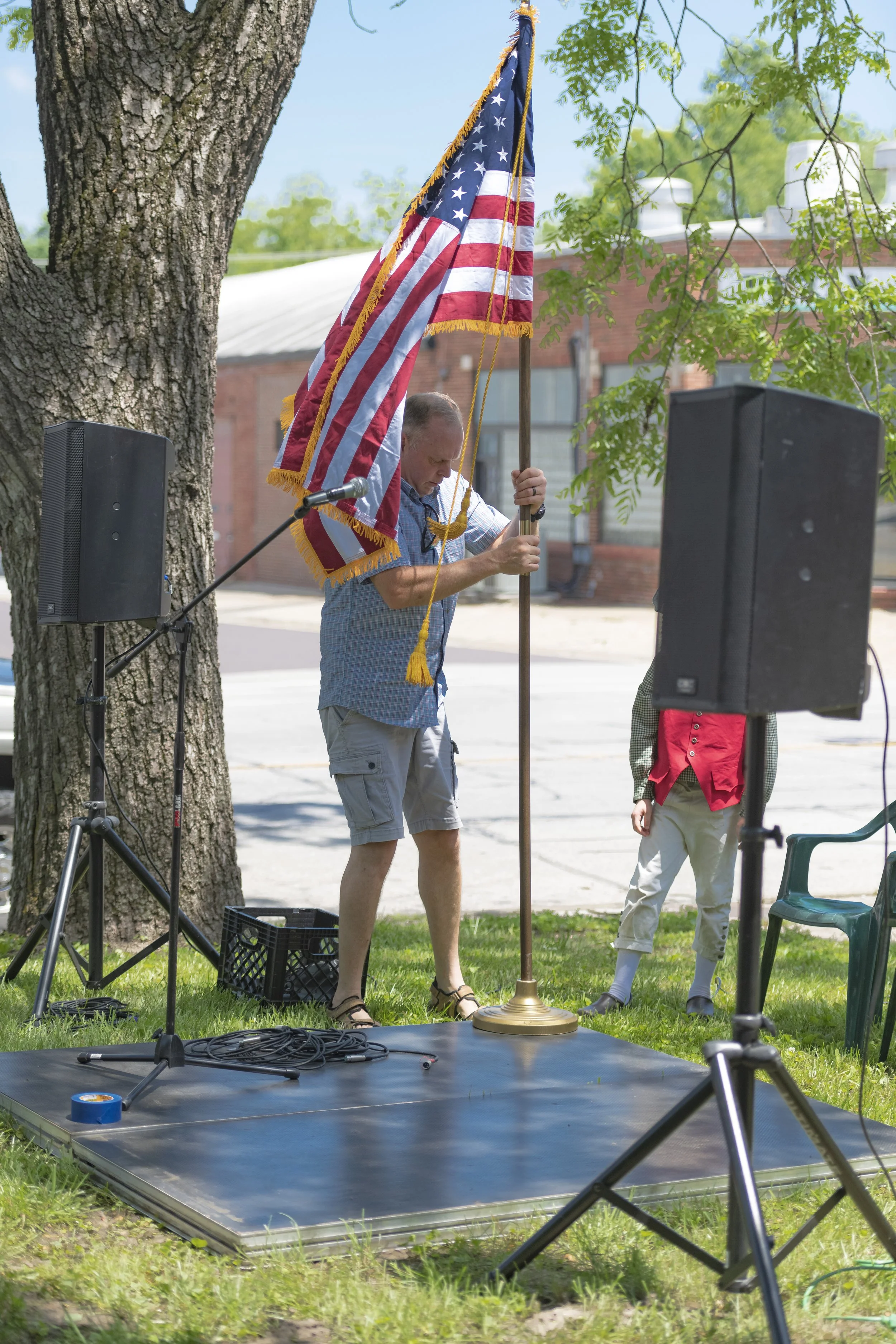 A flag bearer holds an American flag beside the speakers' platform at the 2022 Daughters of the American Revolution ceremony.
