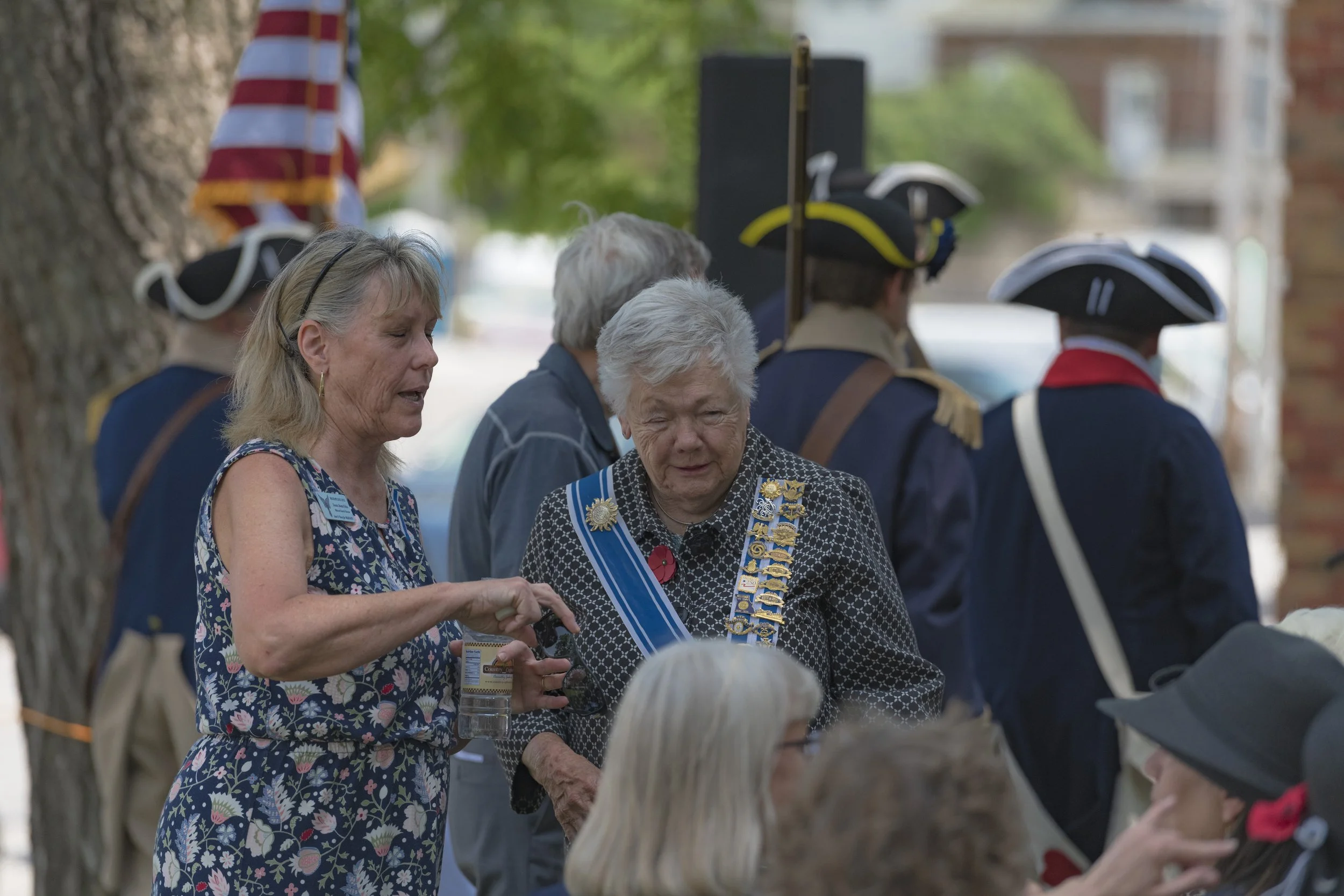 Two attendees talk among the seated guests at the 2022 Daughters of the American Revolution ceremony.