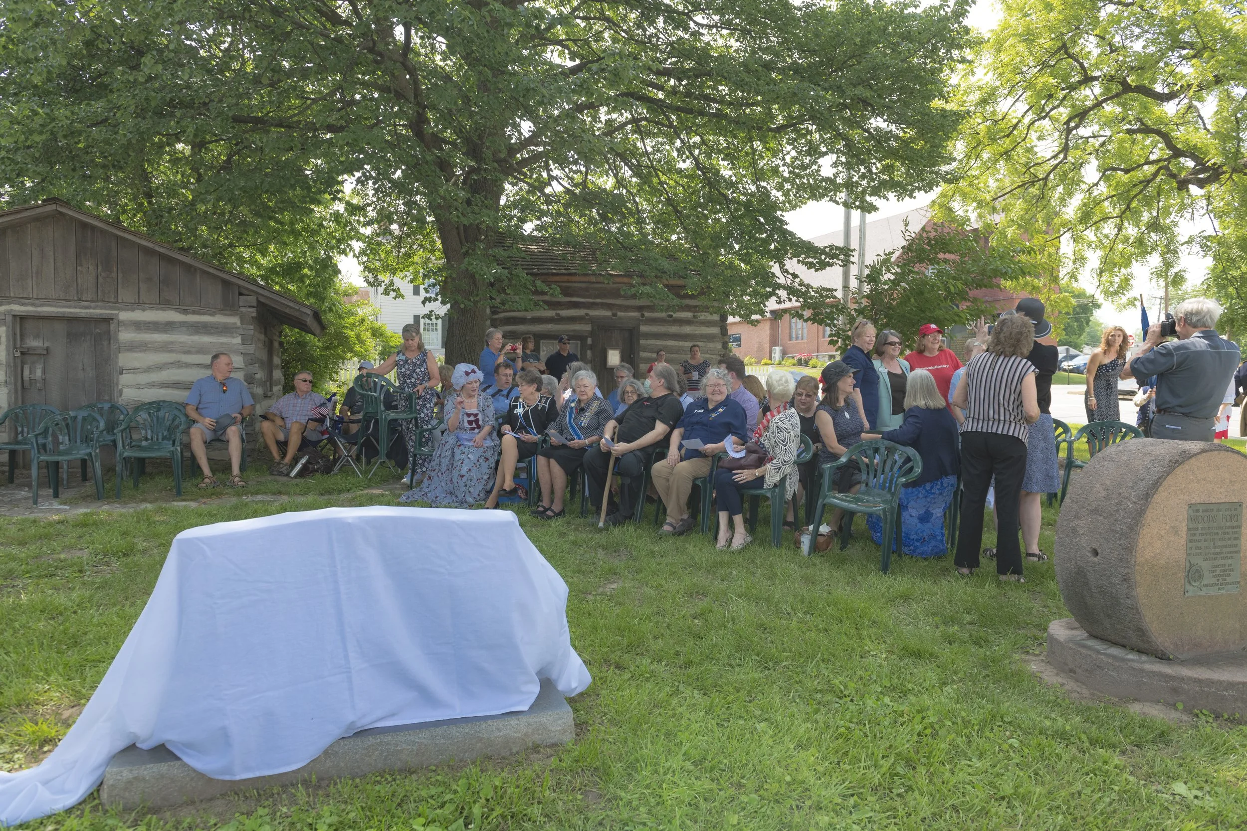 Rows of attendees face a cloth-covered marker on the lawn at the 2022 Daughters of the American Revolution ceremony.
