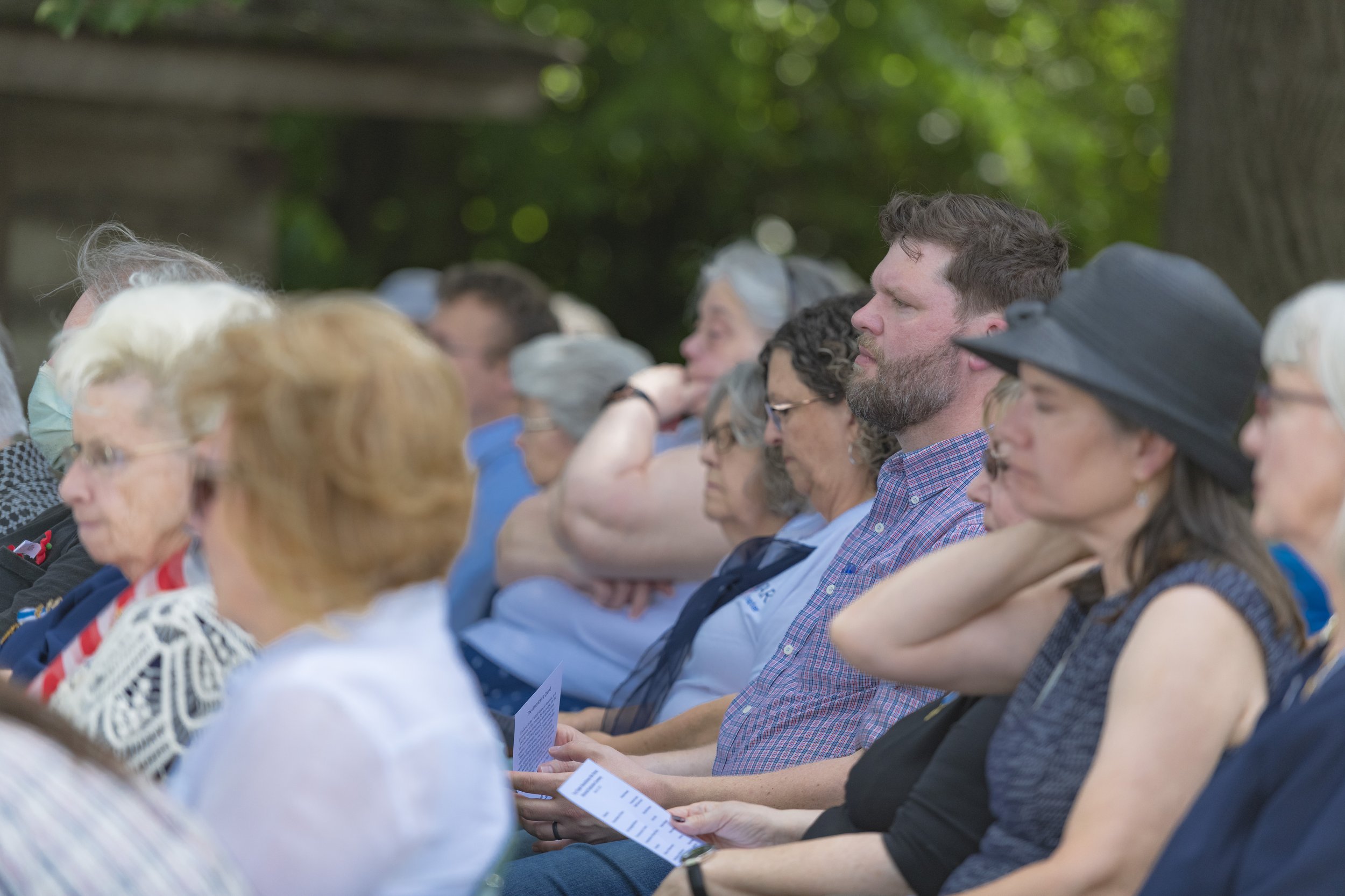Guests listen from their seats, several holding printed programs at the 2022 Daughters of the American Revolution ceremony.