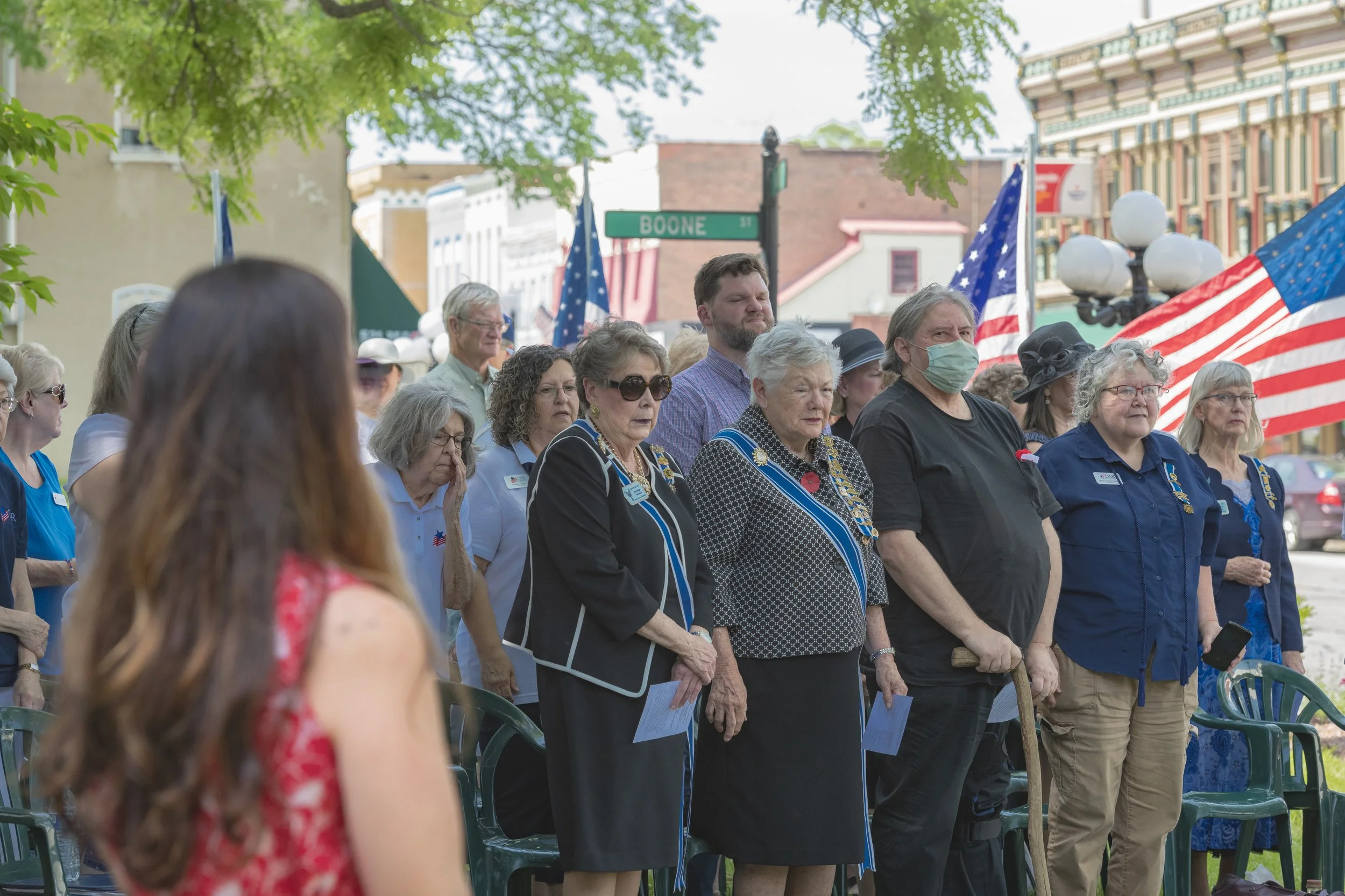Attendees stand together with American flags behind them at the 2022 Daughters of the American Revolution ceremony.