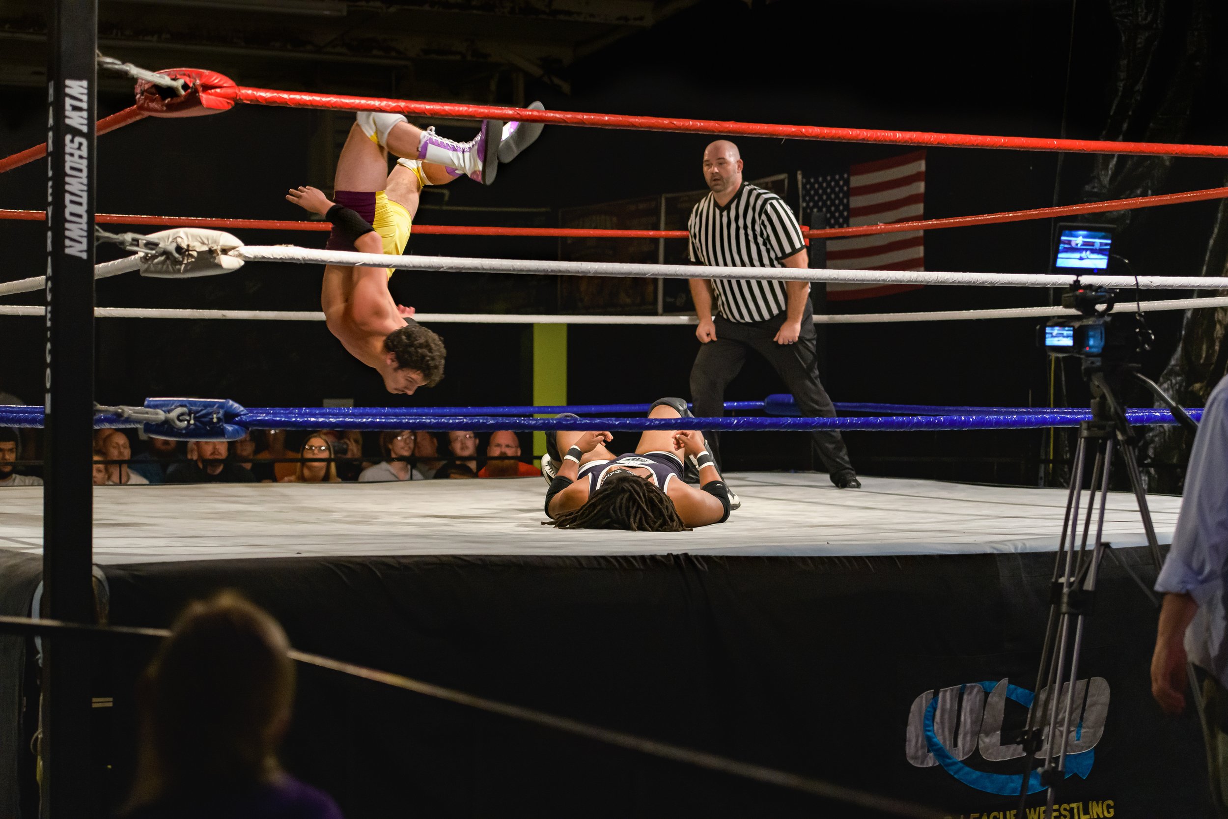 A wrestler rotates upside down above an opponent lying on the mat at the 2022 World League Wrestling event.
