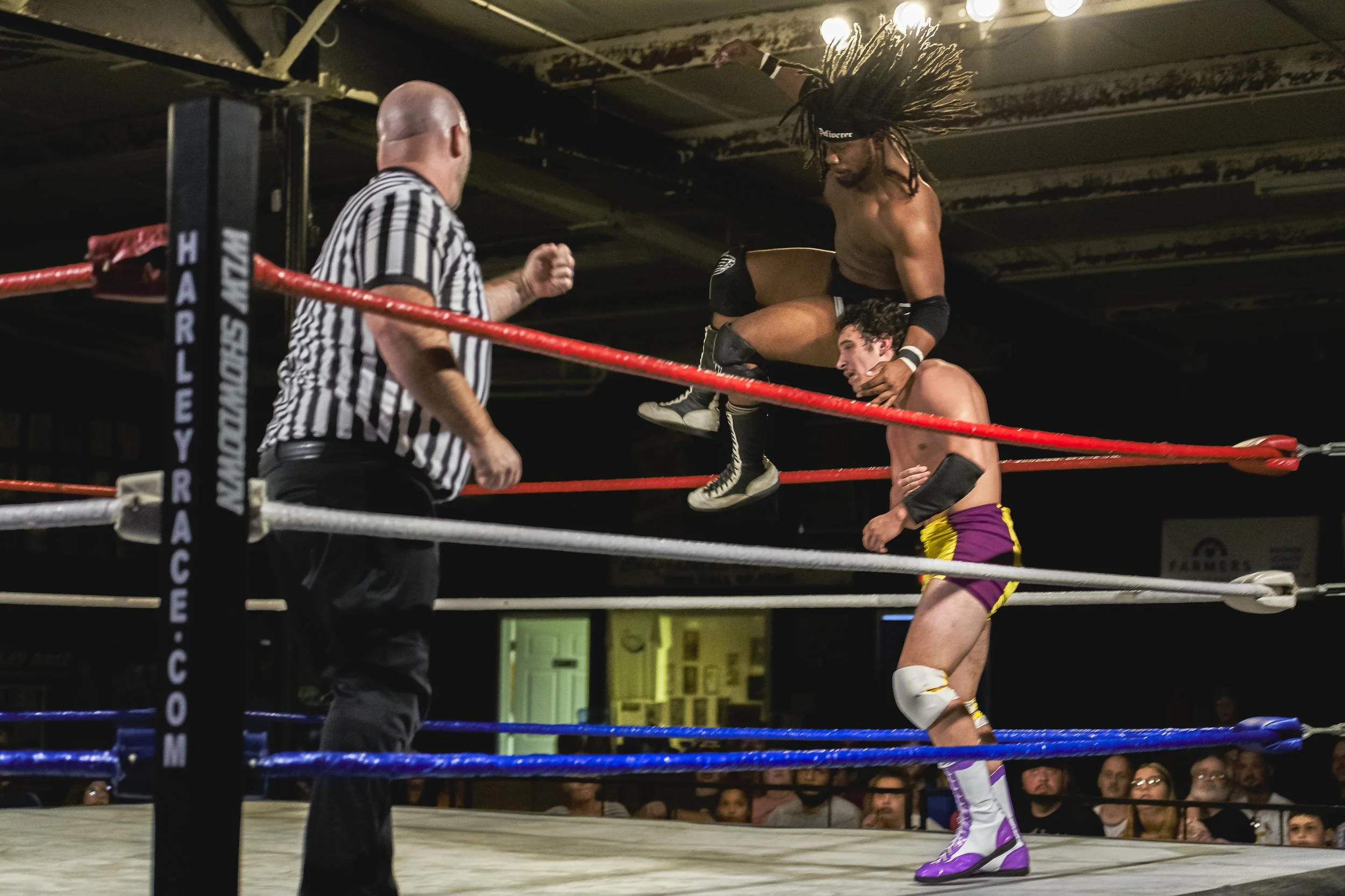 An airborne wrestler moves toward an opponent near the ring corner at the 2022 World League Wrestling event.