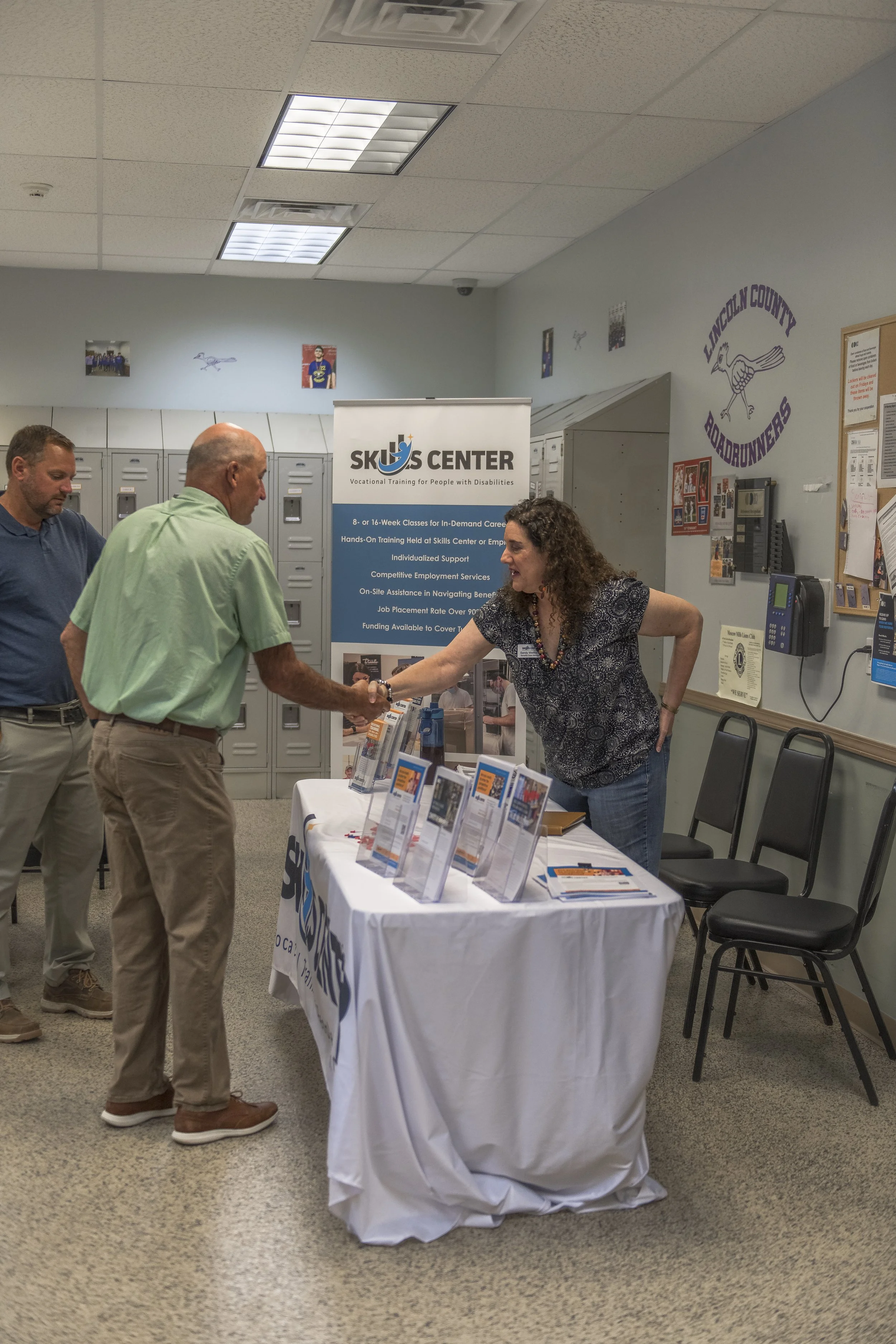 An attendee shakes hands with a representative at a Skills Center information table at the 2022 BCI Open House.