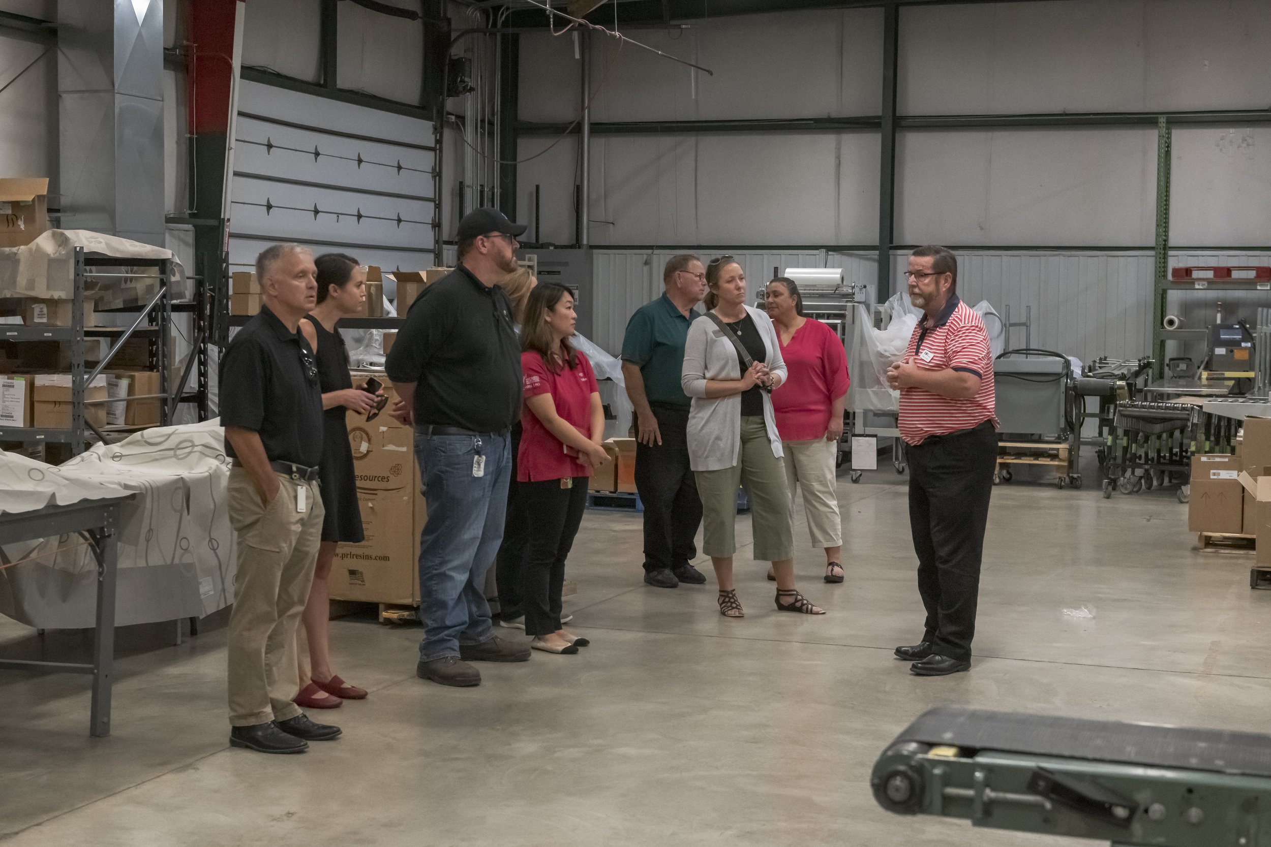 A speaker in a striped shirt addresses visitors beside the production equipment at the 2022 BCI Open House.