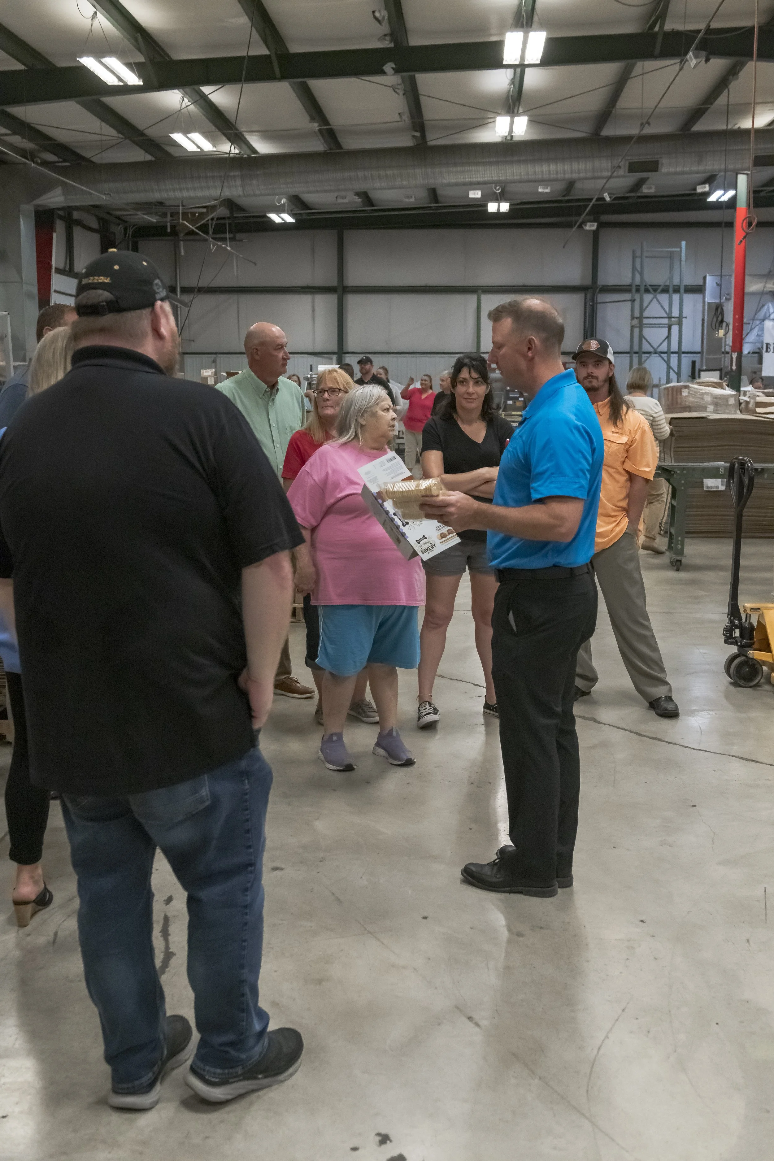 A guide holds printed materials while speaking to a tour group at the 2022 BCI Open House.