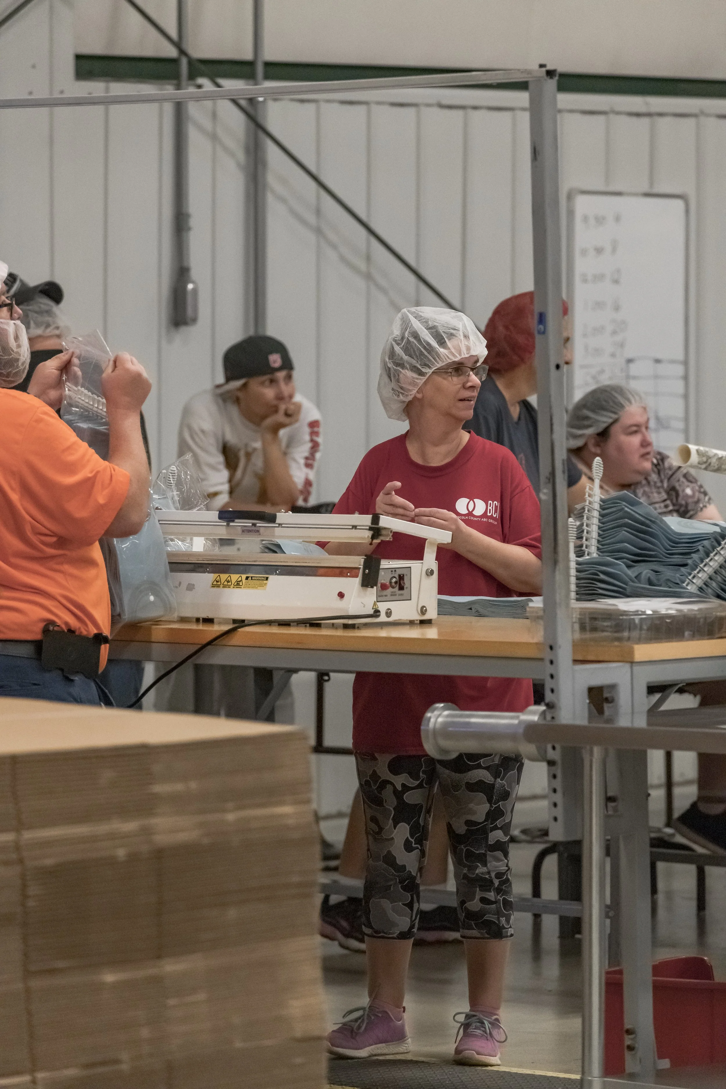 A worker stands at a production station as visitors watch nearby at the 2022 BCI Open House.