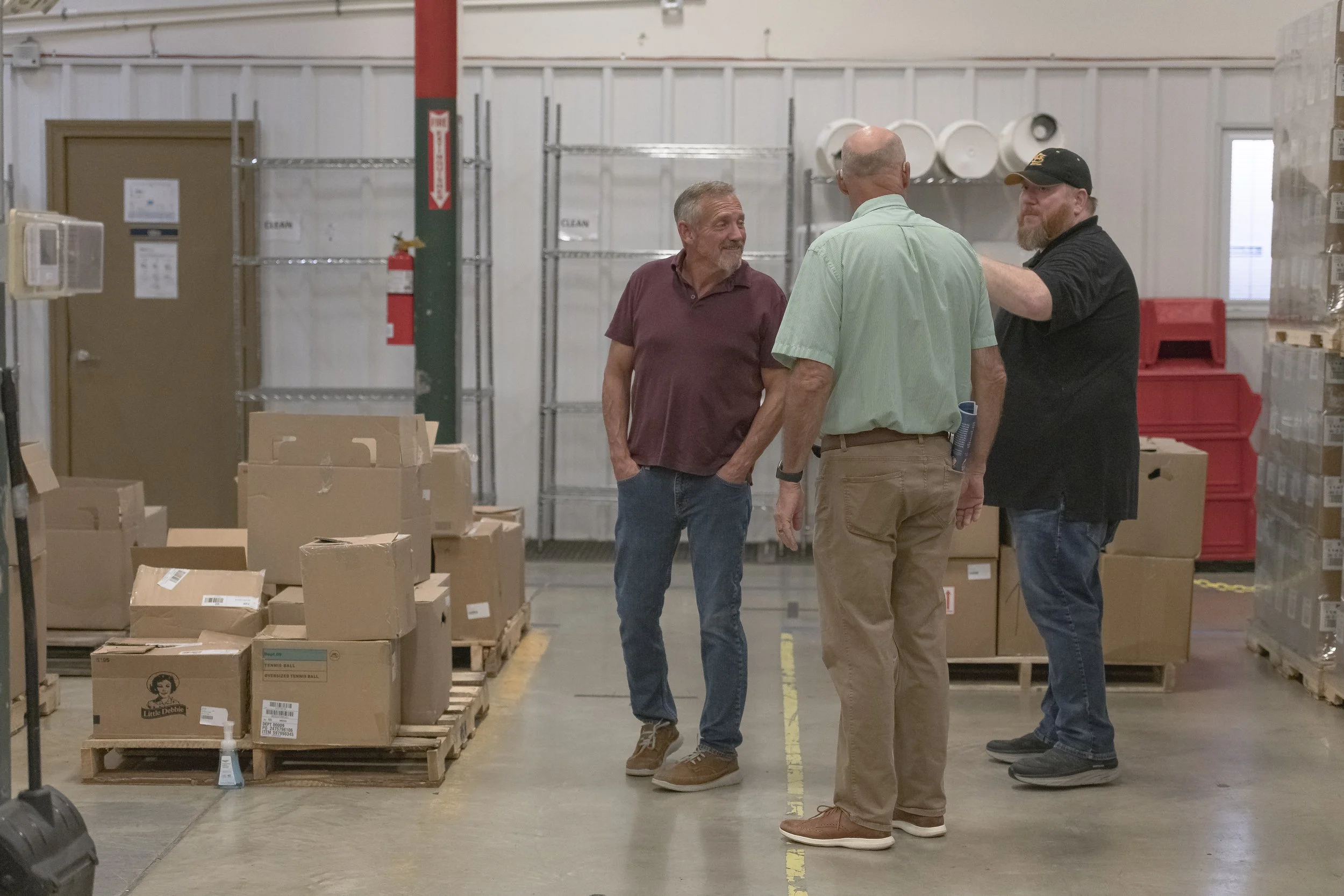 Three attendees talk beside palletized boxes at the 2022 BCI Open House.