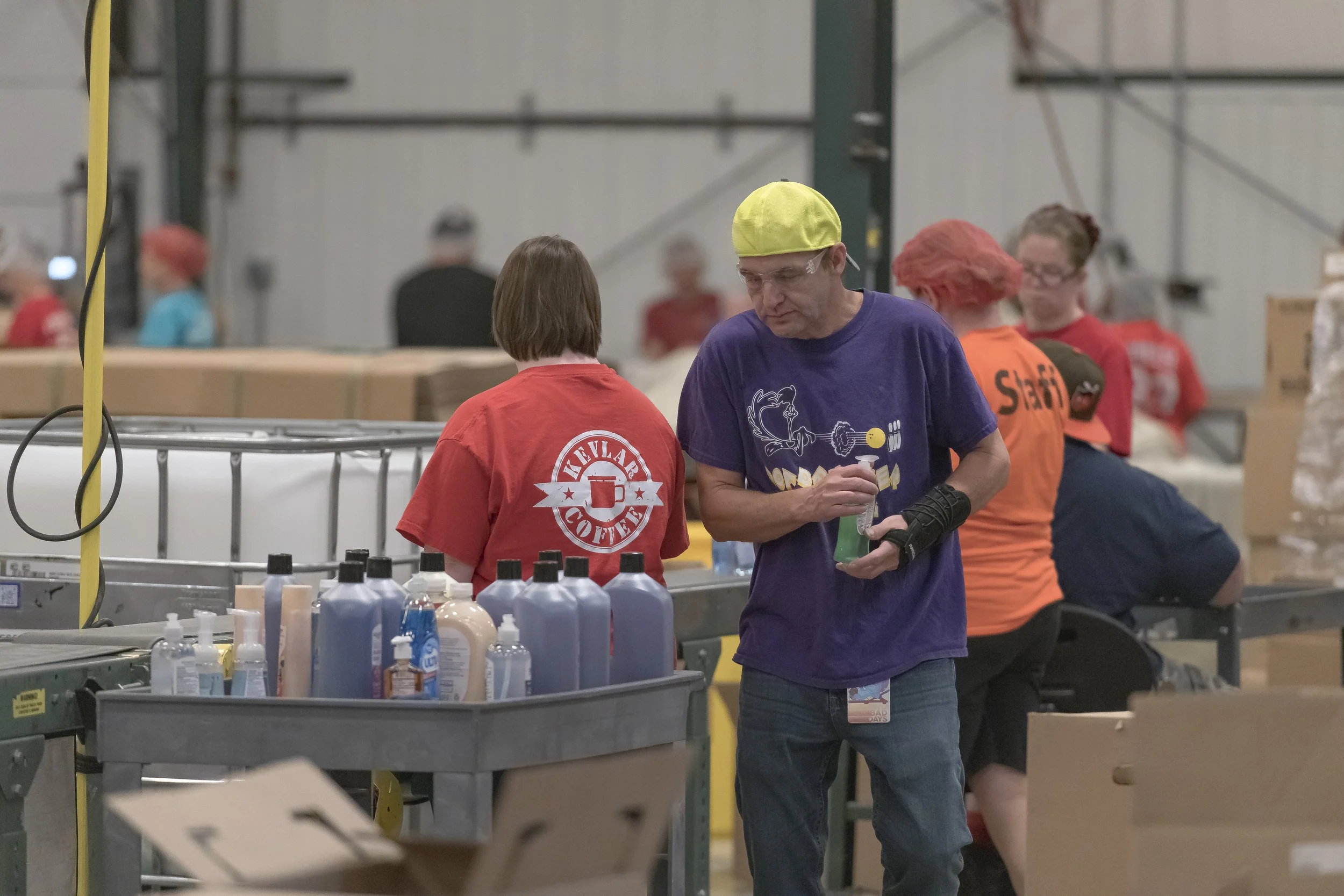 A worker holds a bottle beside a conveyor lined with products at the 2022 BCI Open House.