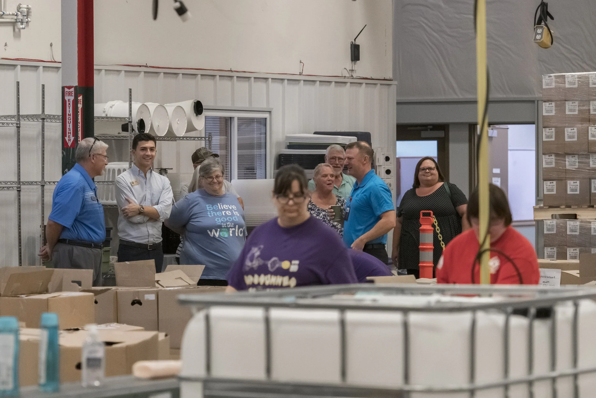 A tour group watches activity beyond a row of production equipment at the 2022 BCI Open House.