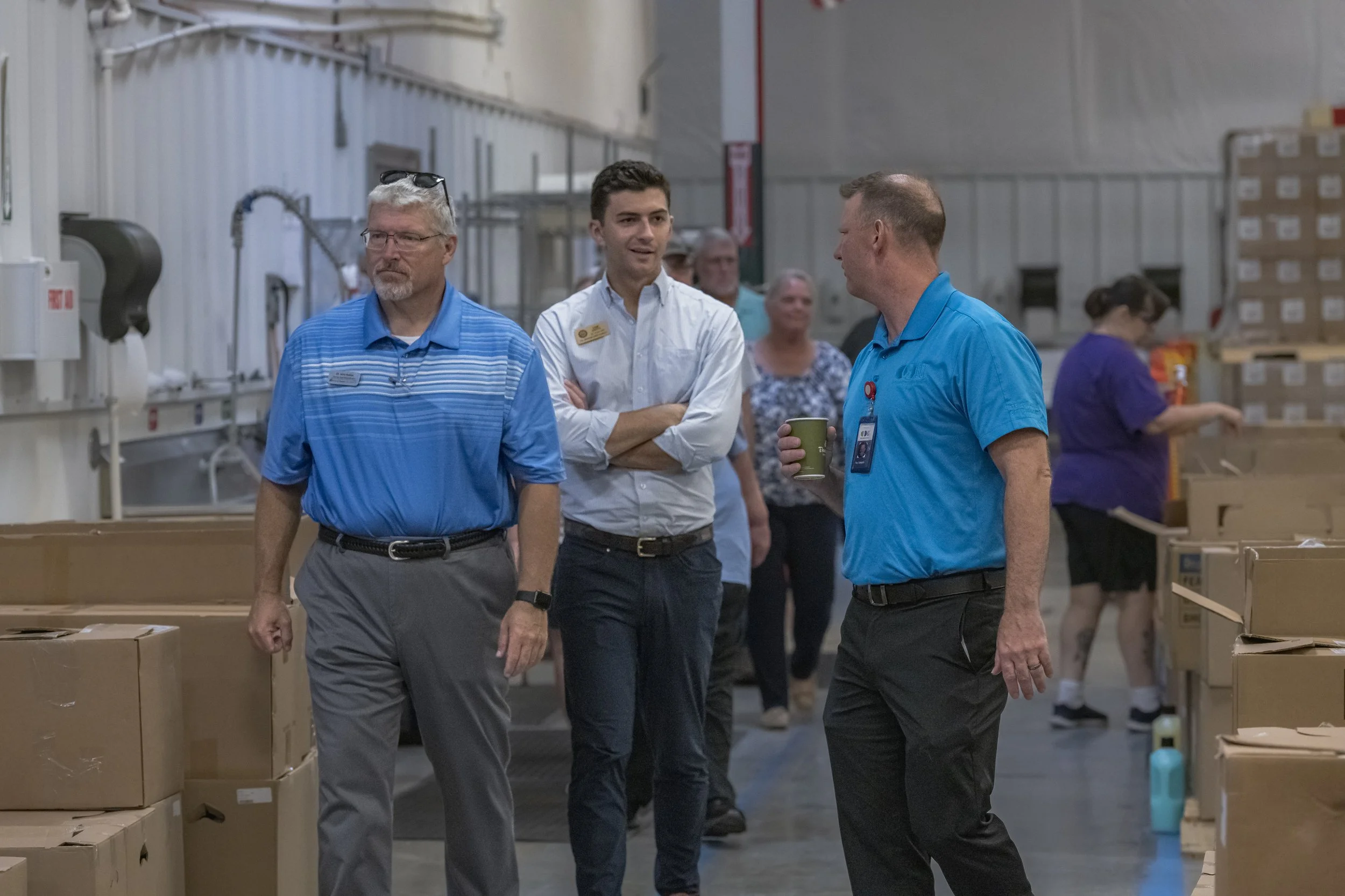Three attendees walk through an aisle between cartons at the 2022 BCI Open House.