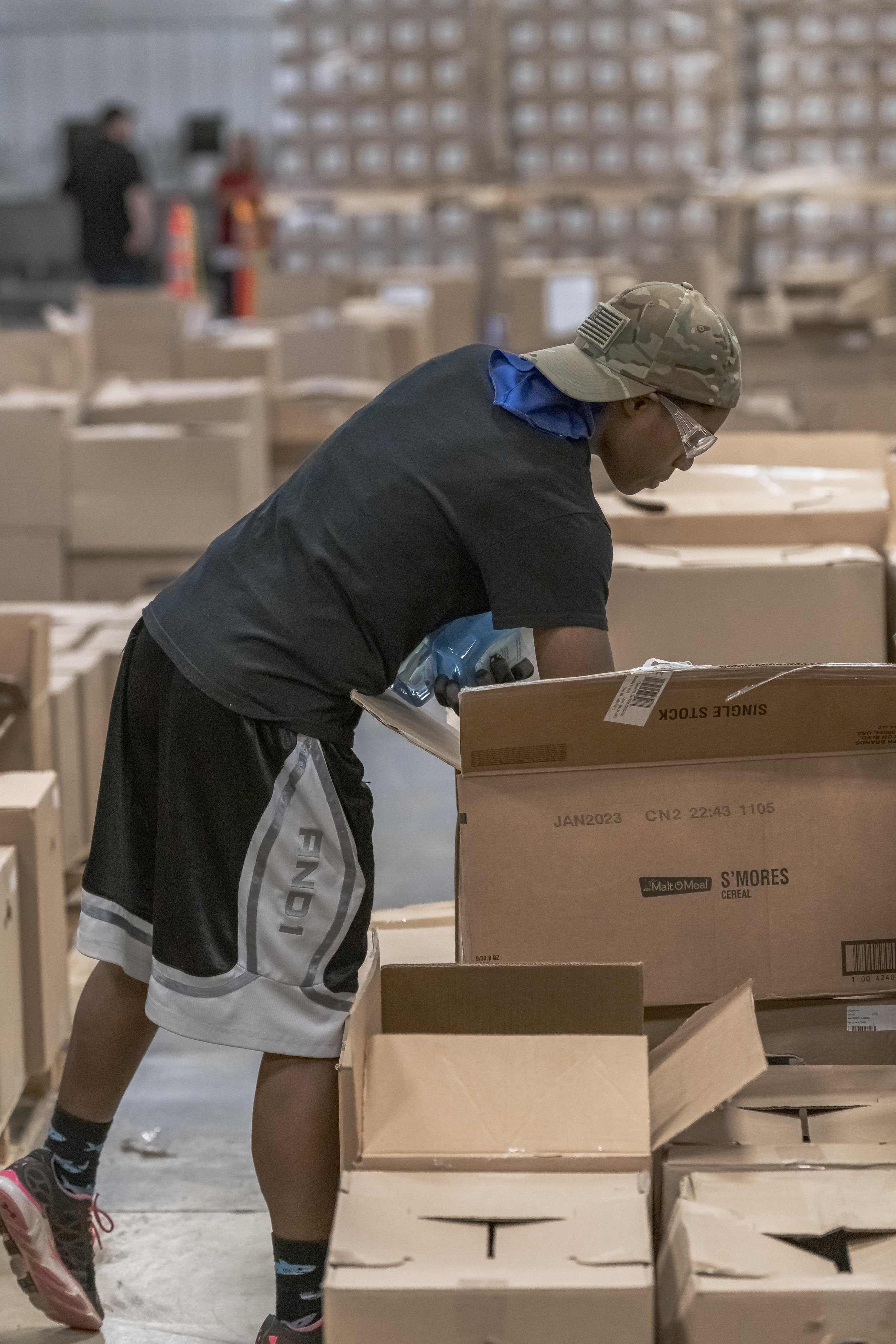 A worker leans over an open carton at a packing station at the 2022 BCI Open House.