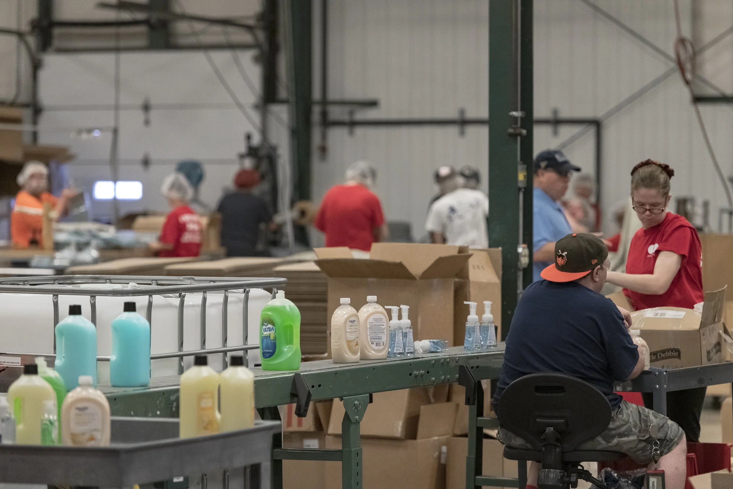 Bottles line a conveyor beside workers packing cartons at the 2022 BCI Open House.