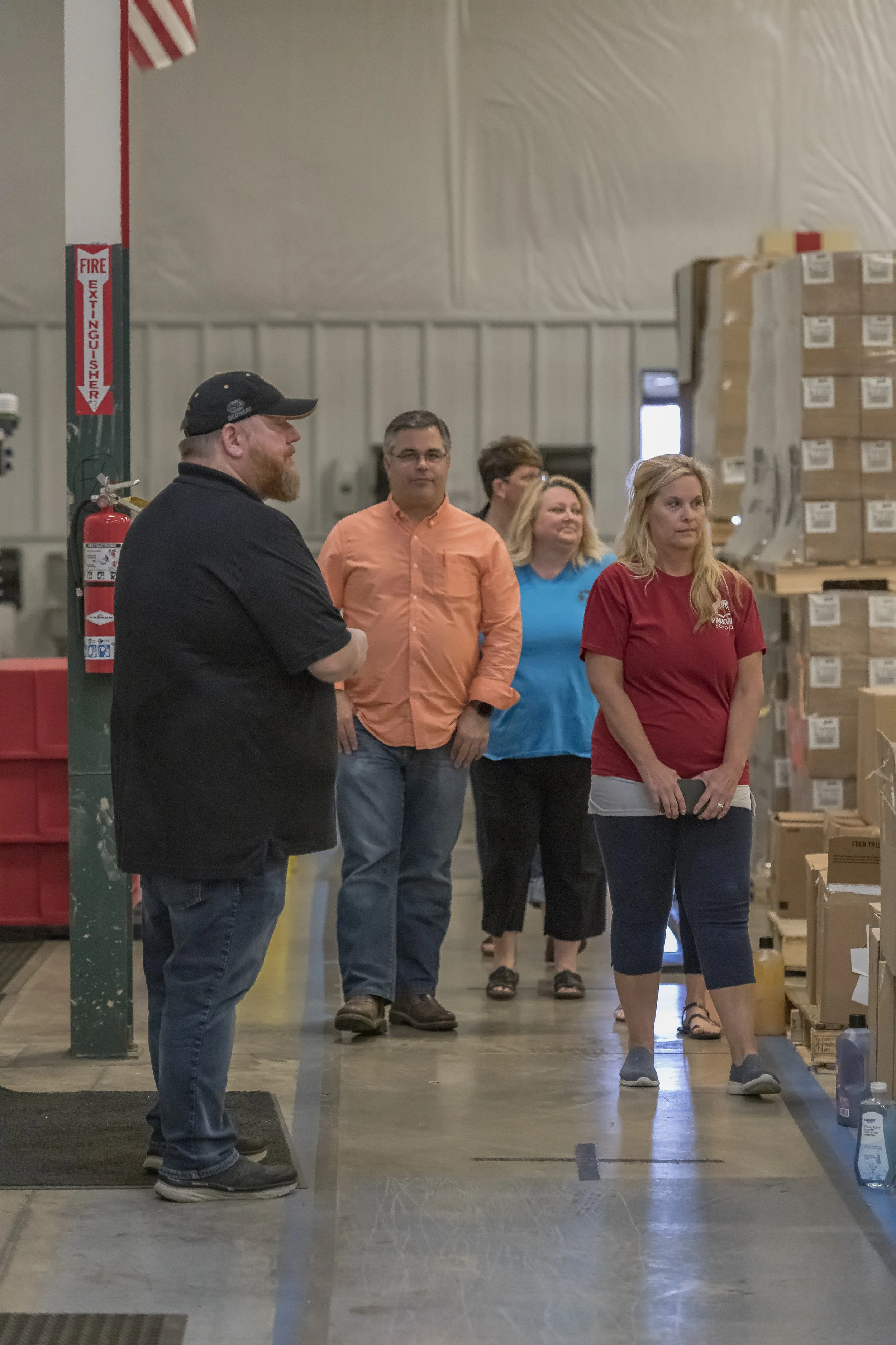 A guide in a black cap addresses visitors in a warehouse aisle at the 2022 BCI Open House.