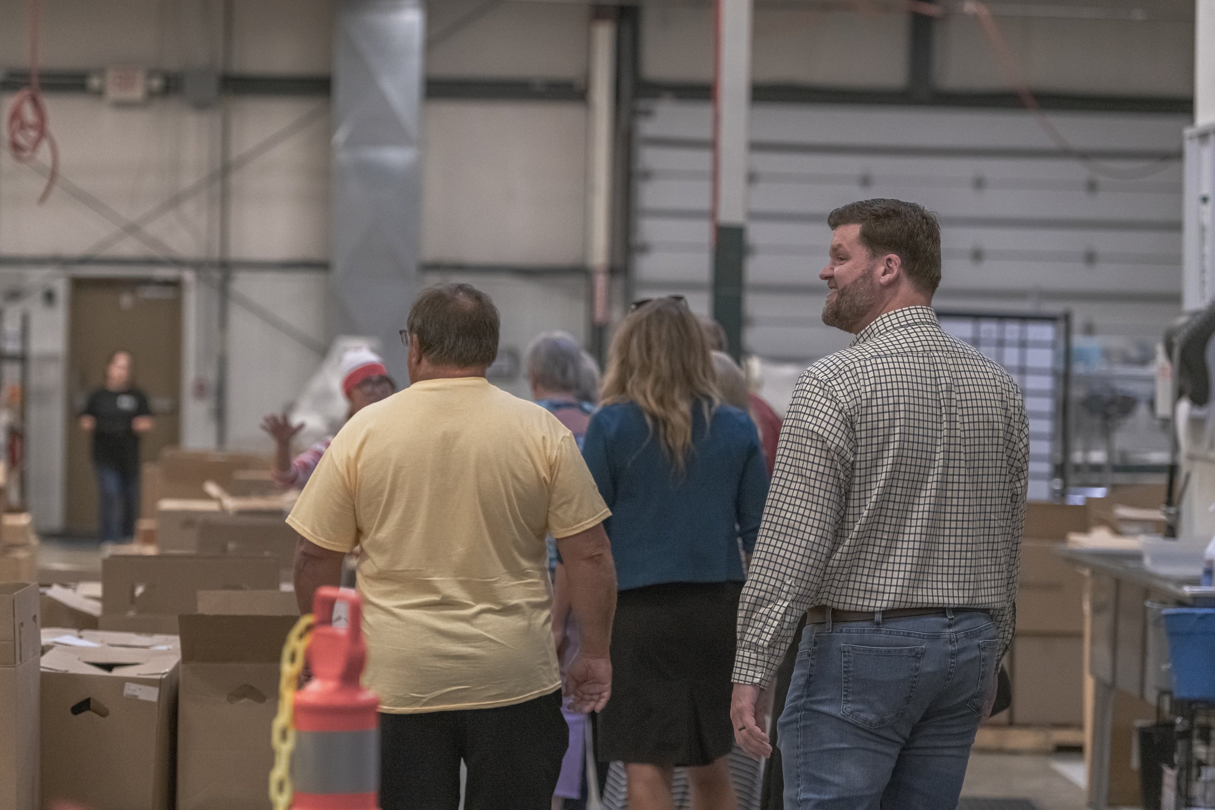 Attendees walk onto the production floor past cartons and workstations at the 2022 BCI Open House.
