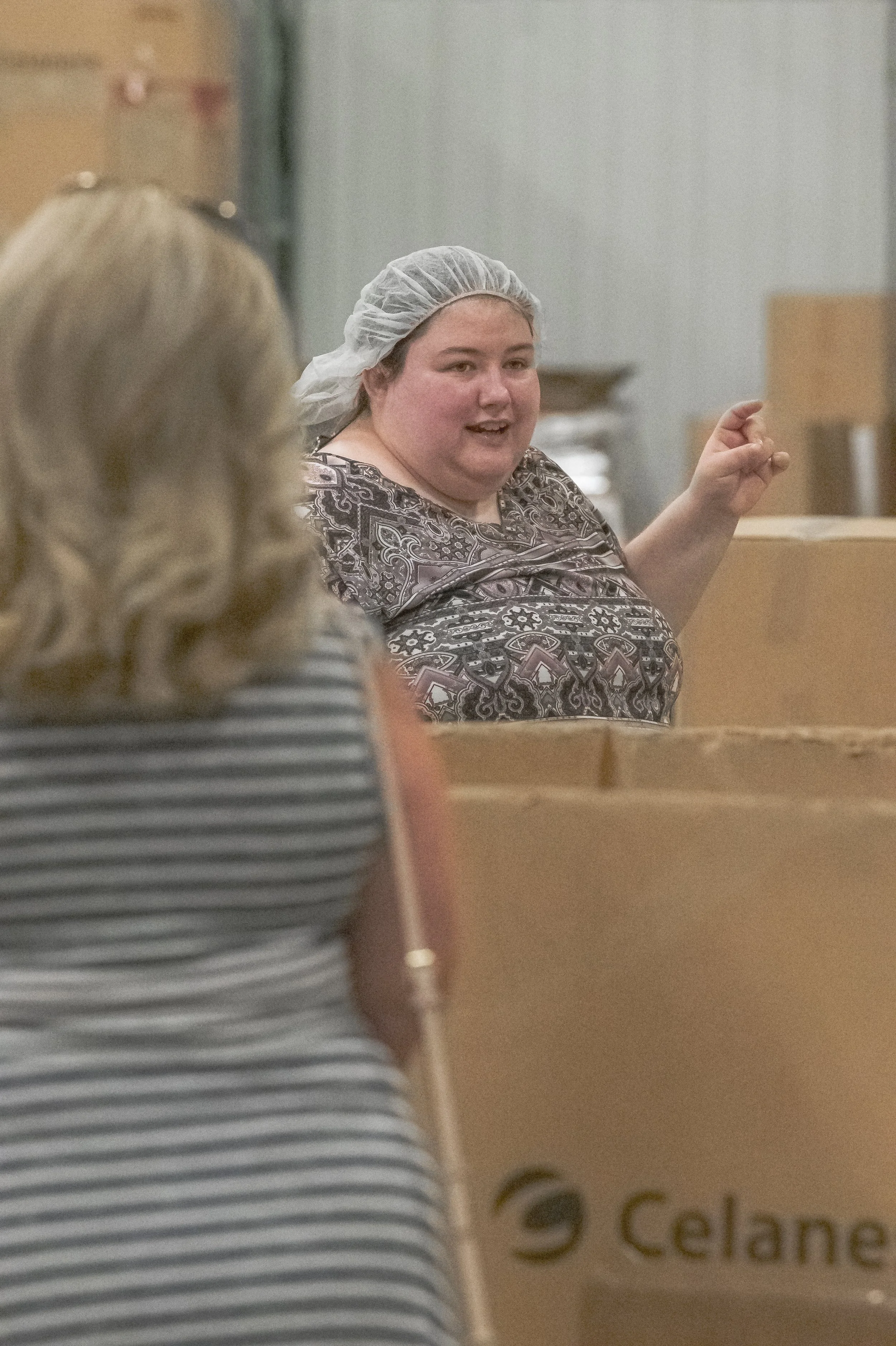 A worker wearing a hairnet gestures beside an open carton at the 2022 BCI Open House.