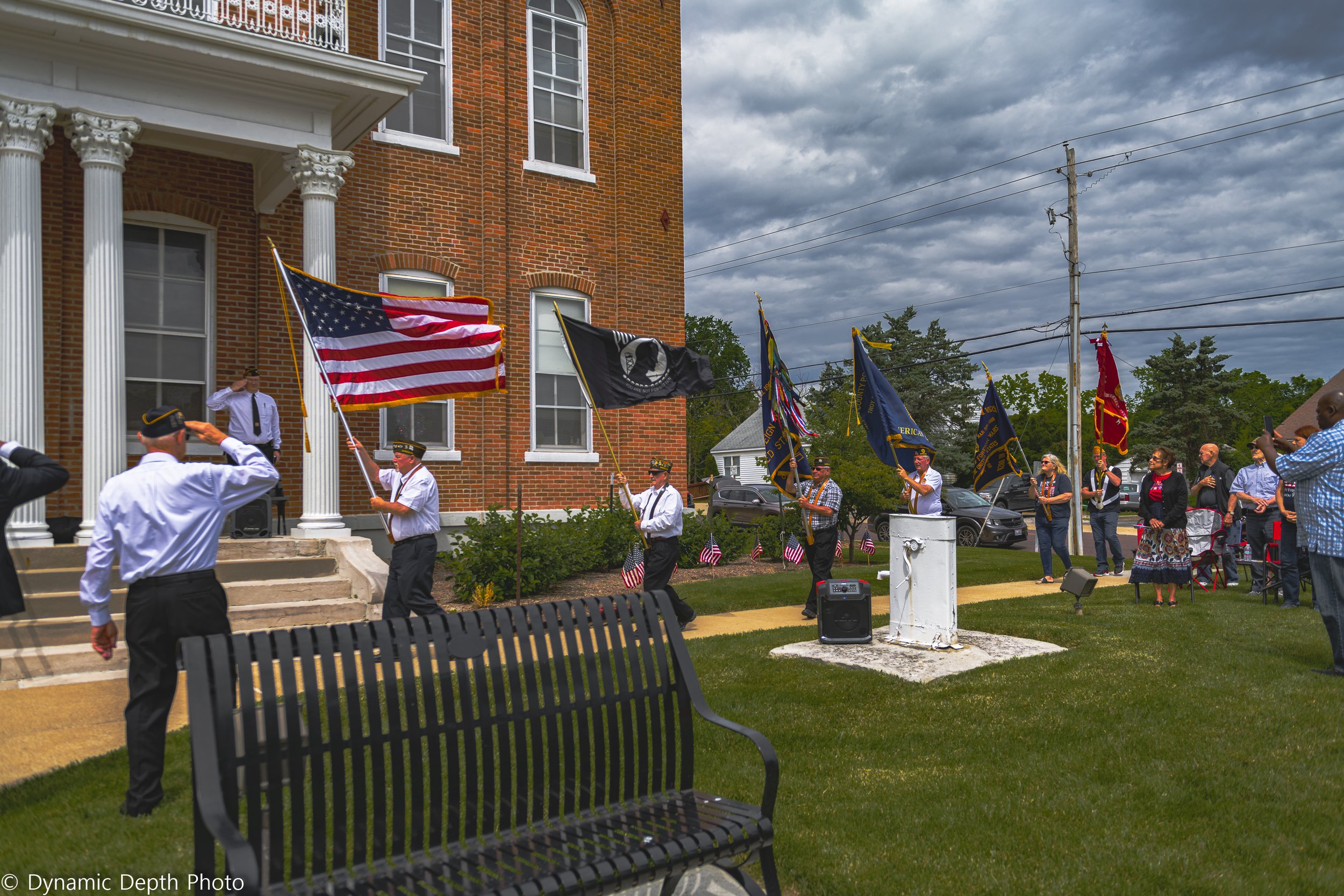 A color guard holds flags on the lawn in front of a columned brick building during the 2021 Memorial Day Service.