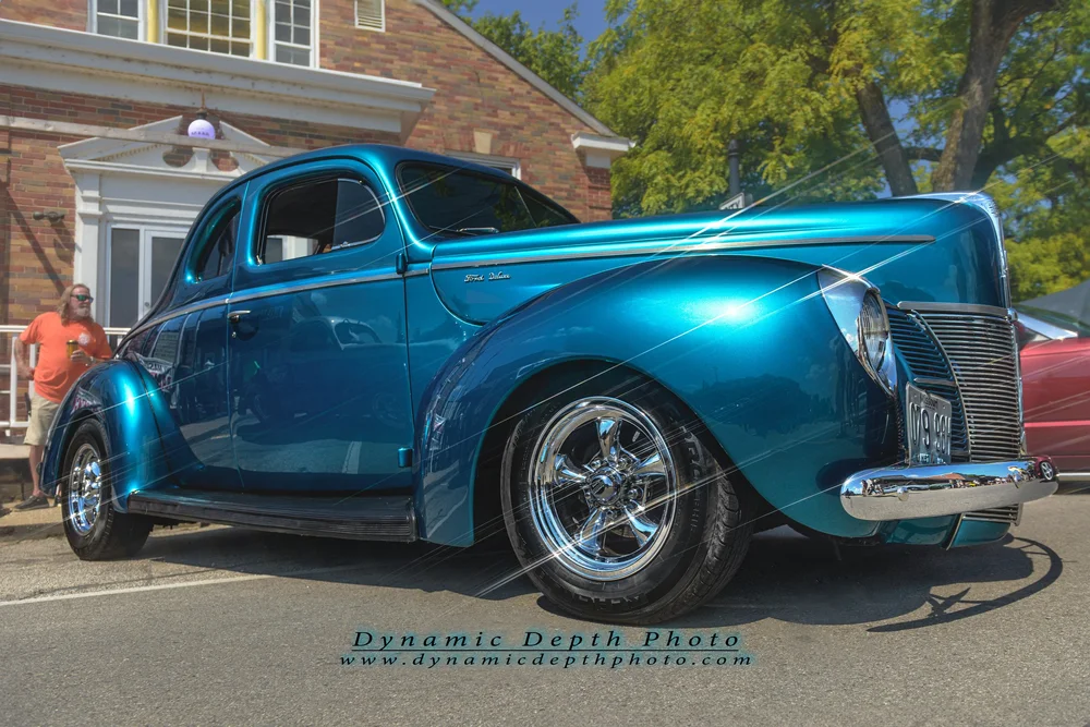 A bright blue vintage coupe with polished chrome wheels.