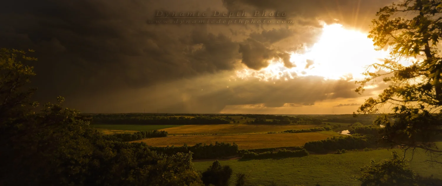 Sunlight Breaking Through Clouds over Fields. Visible: sunlight, dark clouds, fields.