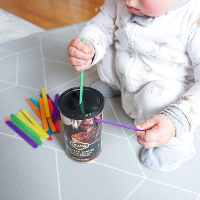 👌🏽 Pop Drop👇🏼 This fine motor activity is so easy to set up! All you need for this 12 mo and up activity is popsicle or craft sticks (a few will do!) and a container you can cut a hole in--I used a cocoa tin. 
Setting up activities like this is a