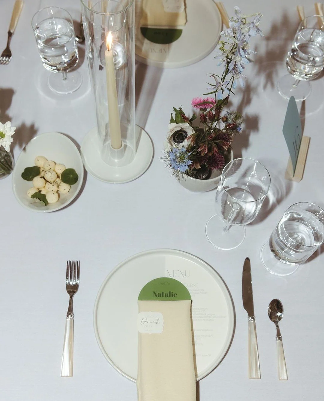 A modern tablescape doesn’t have to fit into just one style box. 
Minimal lines and neutral tones create a clean foundation, while eclectic details, unexpected glassware/silverware, playful florals, and layered textures add personality and w