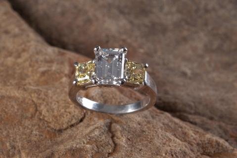 This three stone engagement ring from Secrète's catalog features an internally flawless emerald-cut diamond flanked by fancy yellow internally flawless princess cuts in platinum. Elegance.