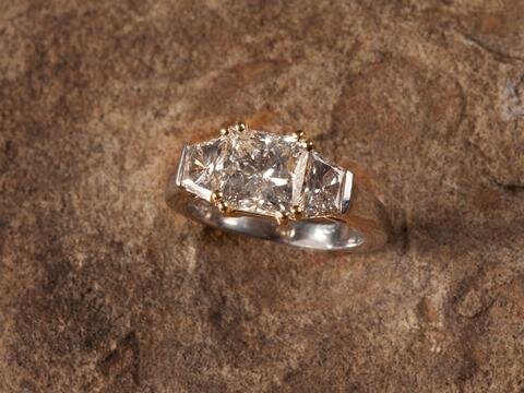 We set this internally flawless princess cut in rose and white gold with trapezoid side stones for a stunning, modern engagement ring in Bethesda.