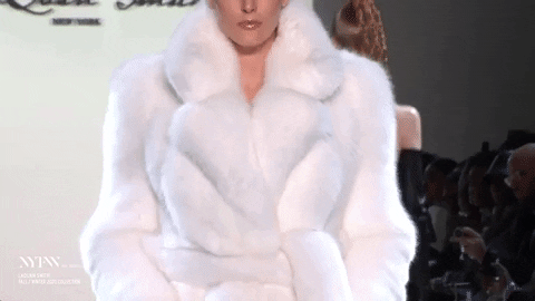 Model walking the New York Fashion Week runway in a white faux fur coat.