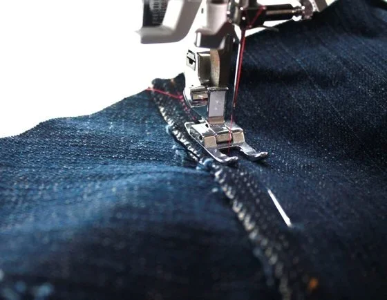 Close-up of a sewing machine stitching denim fabric.