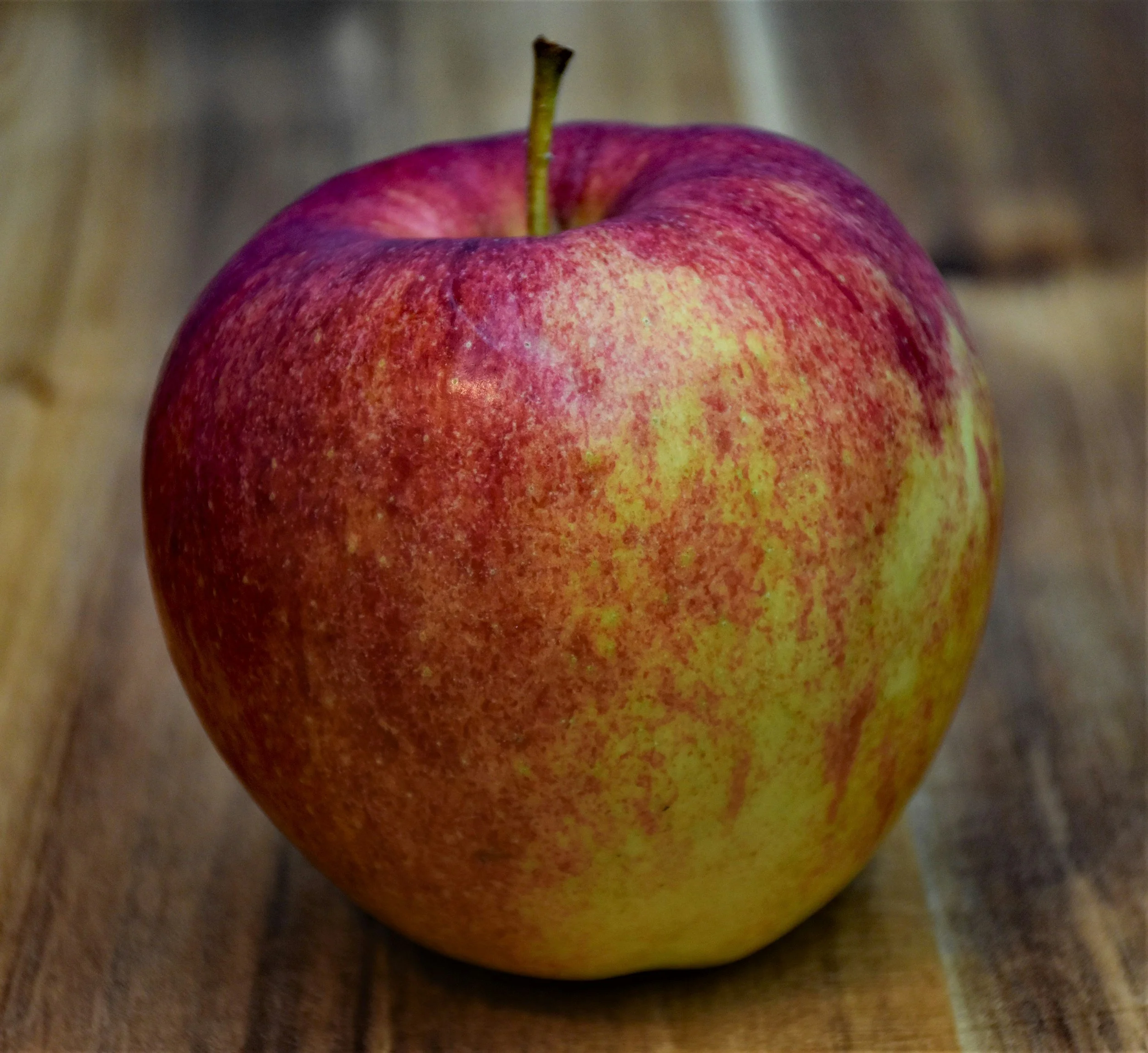 A red and yellow apple on a wooden surface.