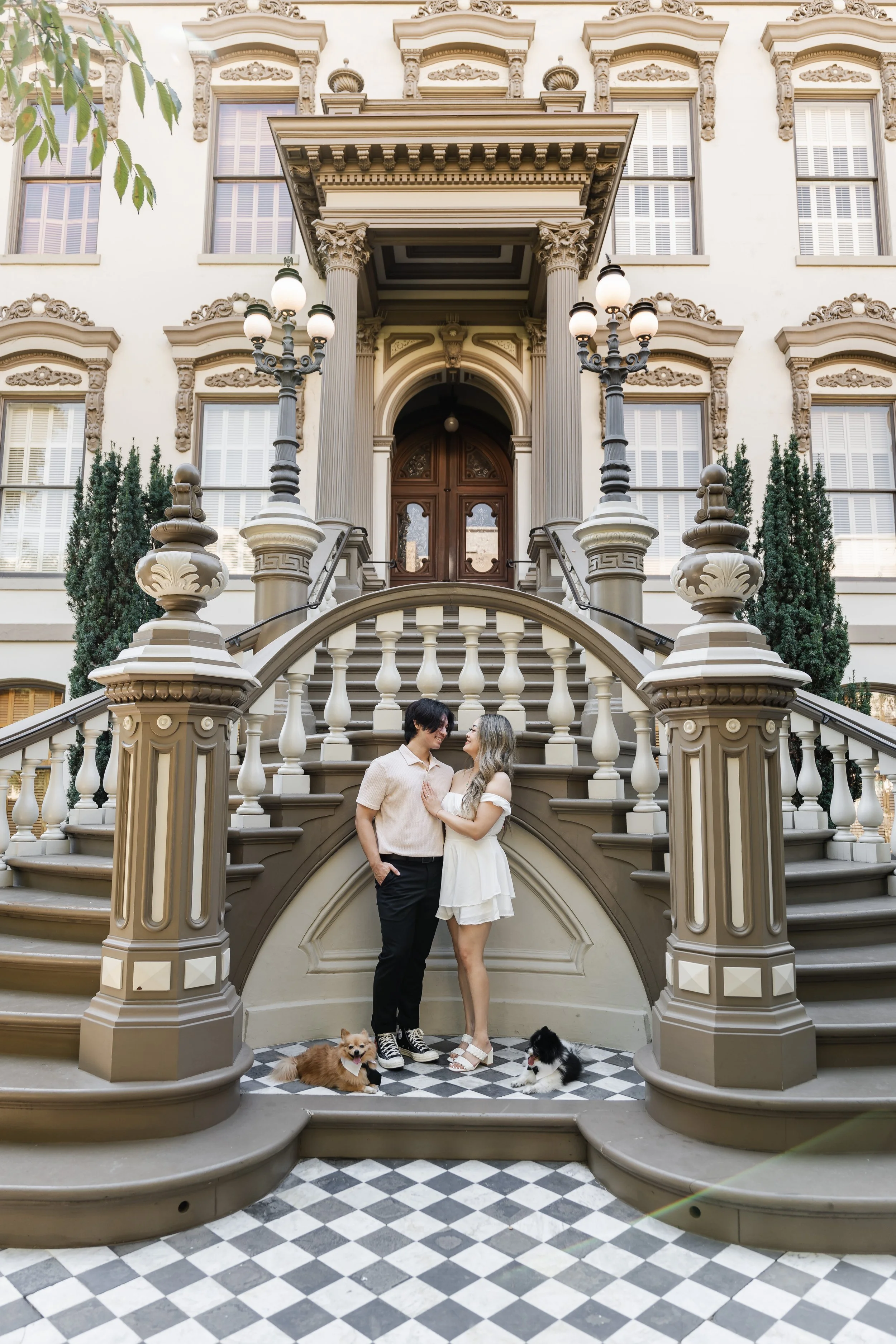 Couple look at each other while their dogs lay on the ground at Leland Stanford Museum in Sacramento California